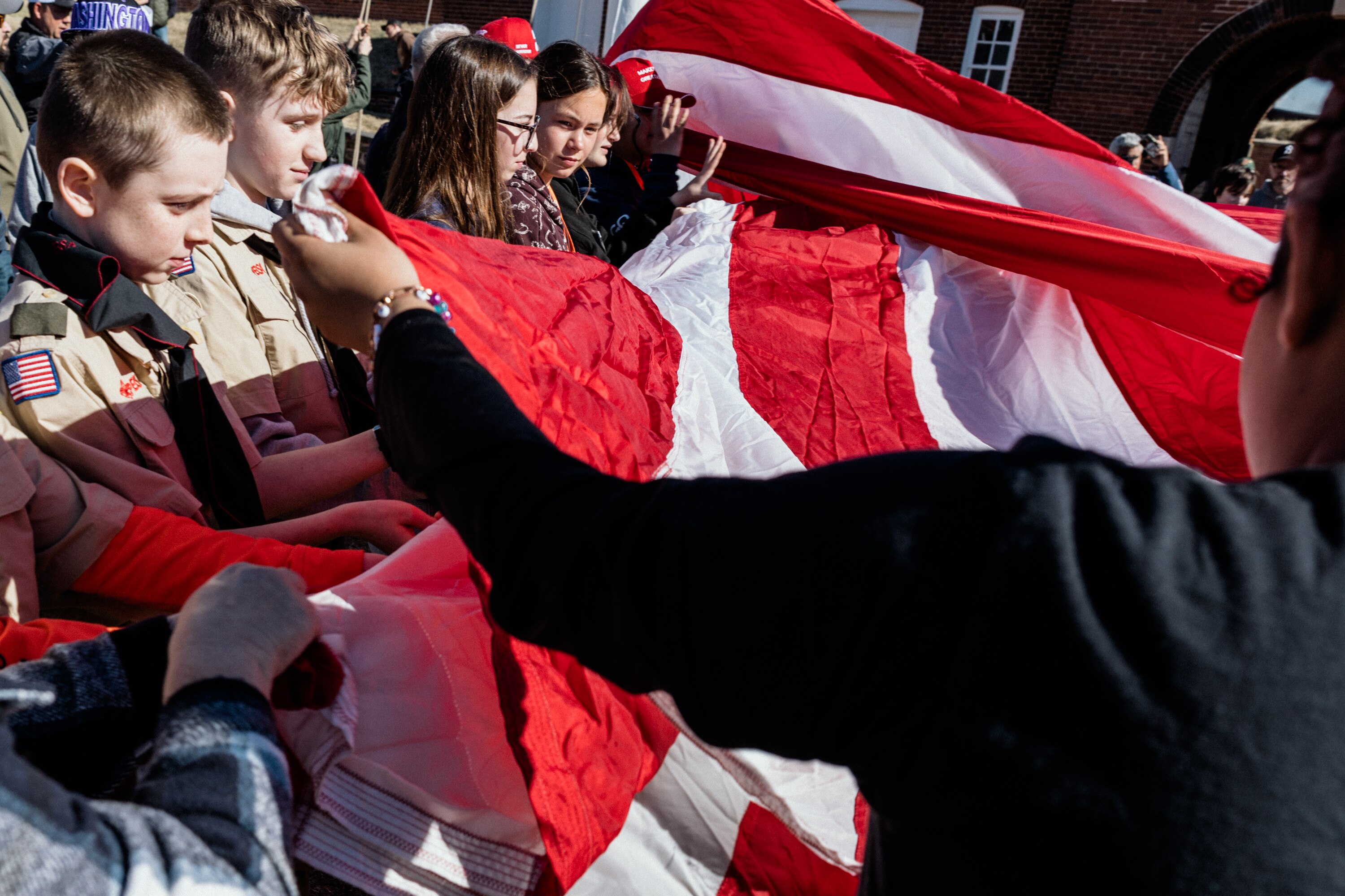 BALTIMORE, MD - March 1, 2025: Visitors unravel a large American flag during the morning flag change at Fort McHenry during the 100th anniversary celebration on March 1, 2025 in Baltimore, Maryland.