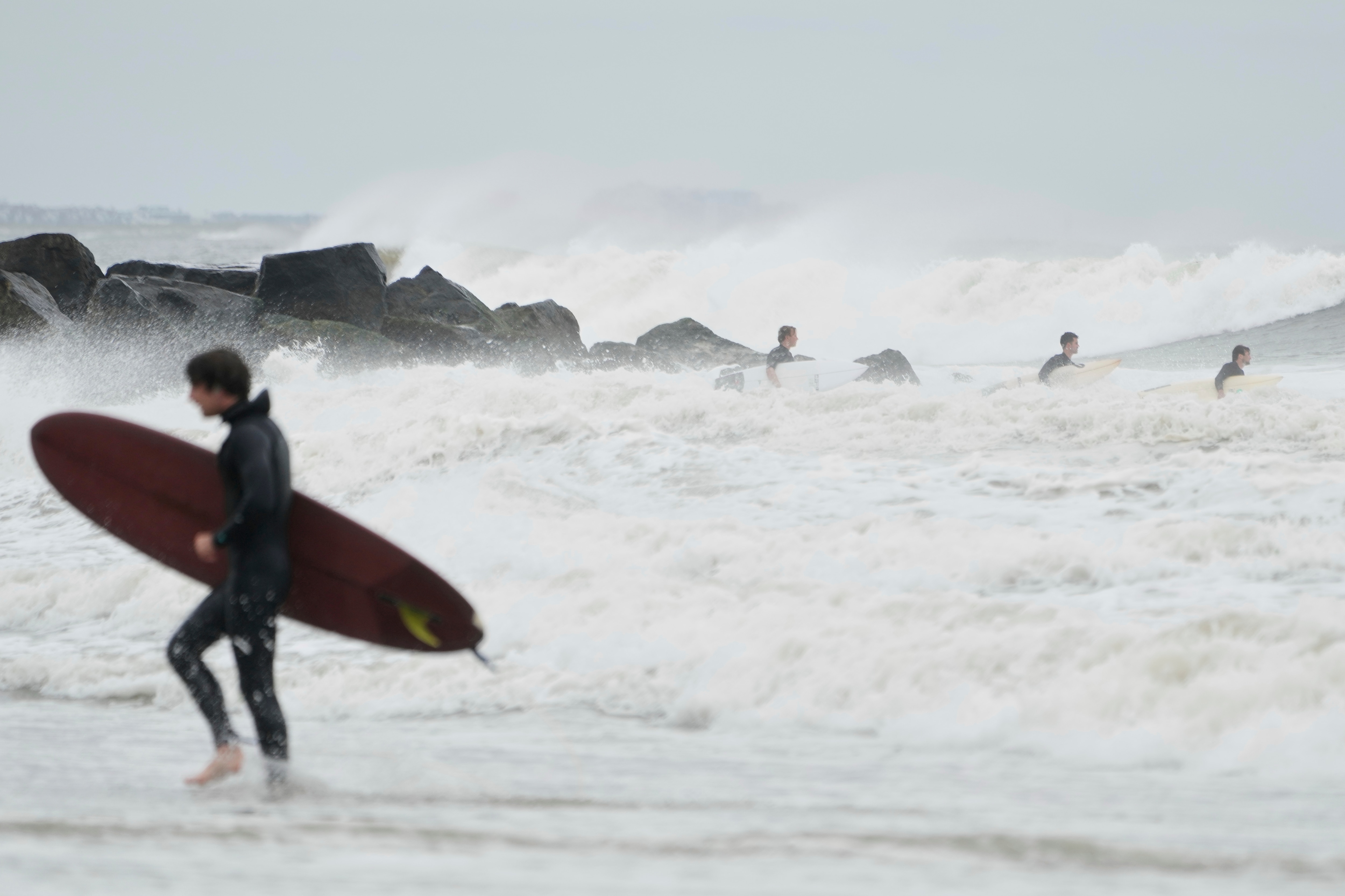 Surfers try to get in the water, past big waves bolstered by Hurricane Erin, at Rockaway Beach in the Queens borough of New York, Thursday, Aug. 21, 2025. (AP Photo/Seth Wenig)