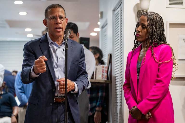 Anthony Brown, left, speaks at the mic and Natasha Dartigue listens.