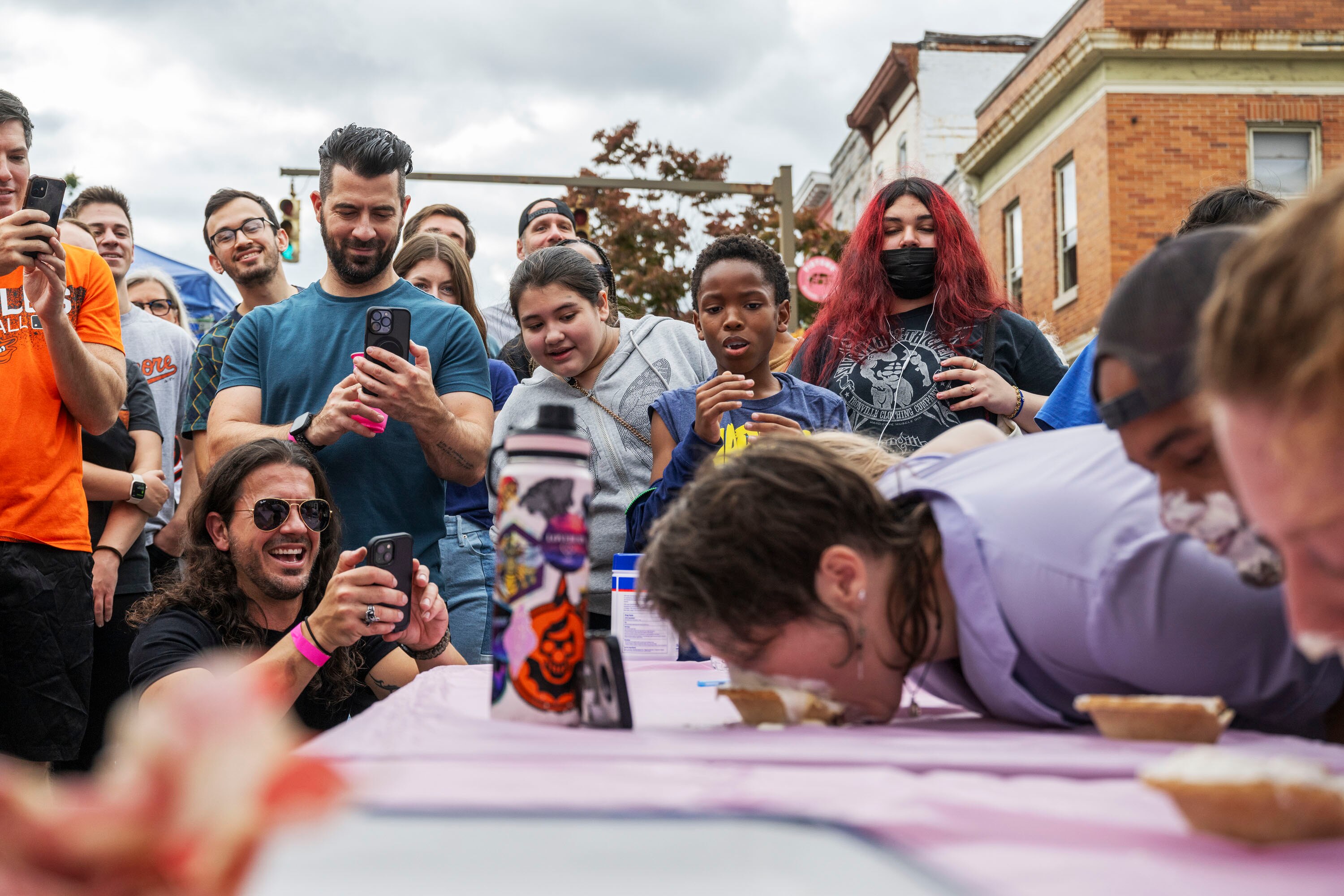 Festival attendees look on as contestants compete in a pie eating contest during the Pigtown Festival in Baltimore, MD on September 30, 2023.