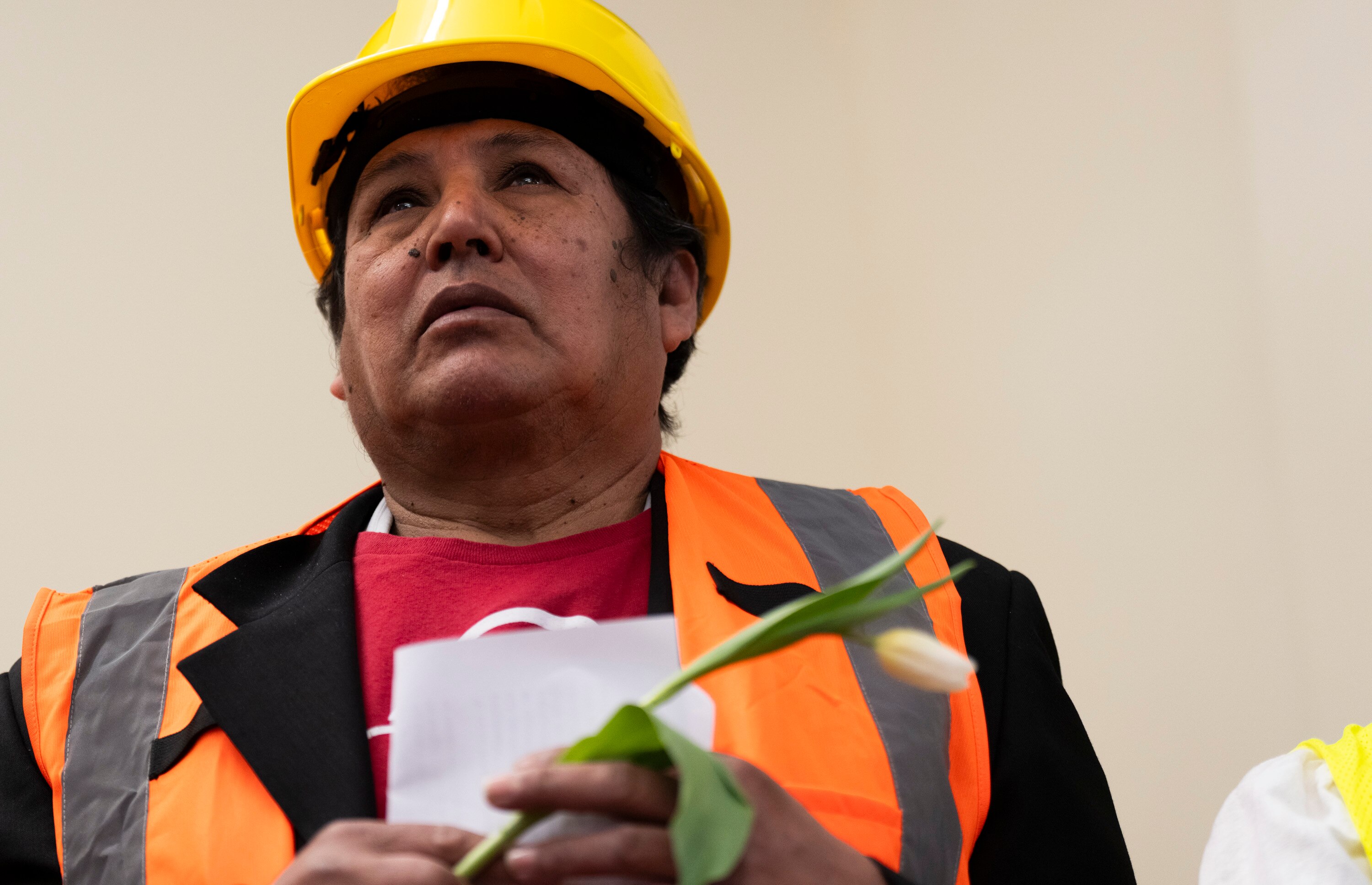 Construction workers honored the Key Bridge victims during a news conference on March 28, 2024 at CASA's Baltimore worker center. They held white lilies and raised their hands in solidarity. Darwin Orlando Lopez, from Honduras, looks on as his colleagues speak.