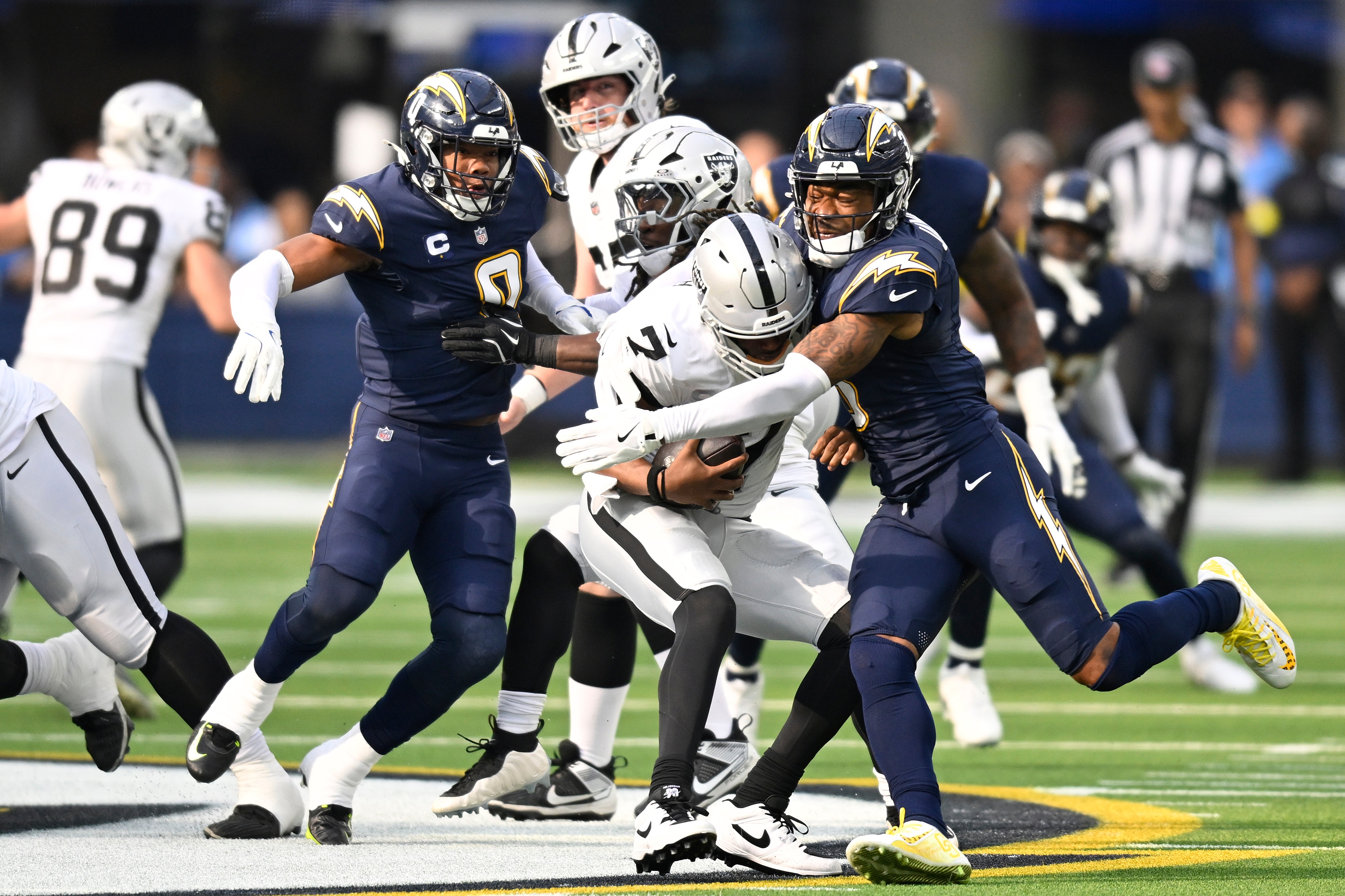 INGLEWOOD, CALIFORNIA - NOVEMBER 30: Daiyan Henley #0 of the Los Angeles Chargers sacks Geno Smith #7 of the Las Vegas Raiders in the first quarter of a game at SoFi Stadium on November 30, 2025 in Inglewood, California.