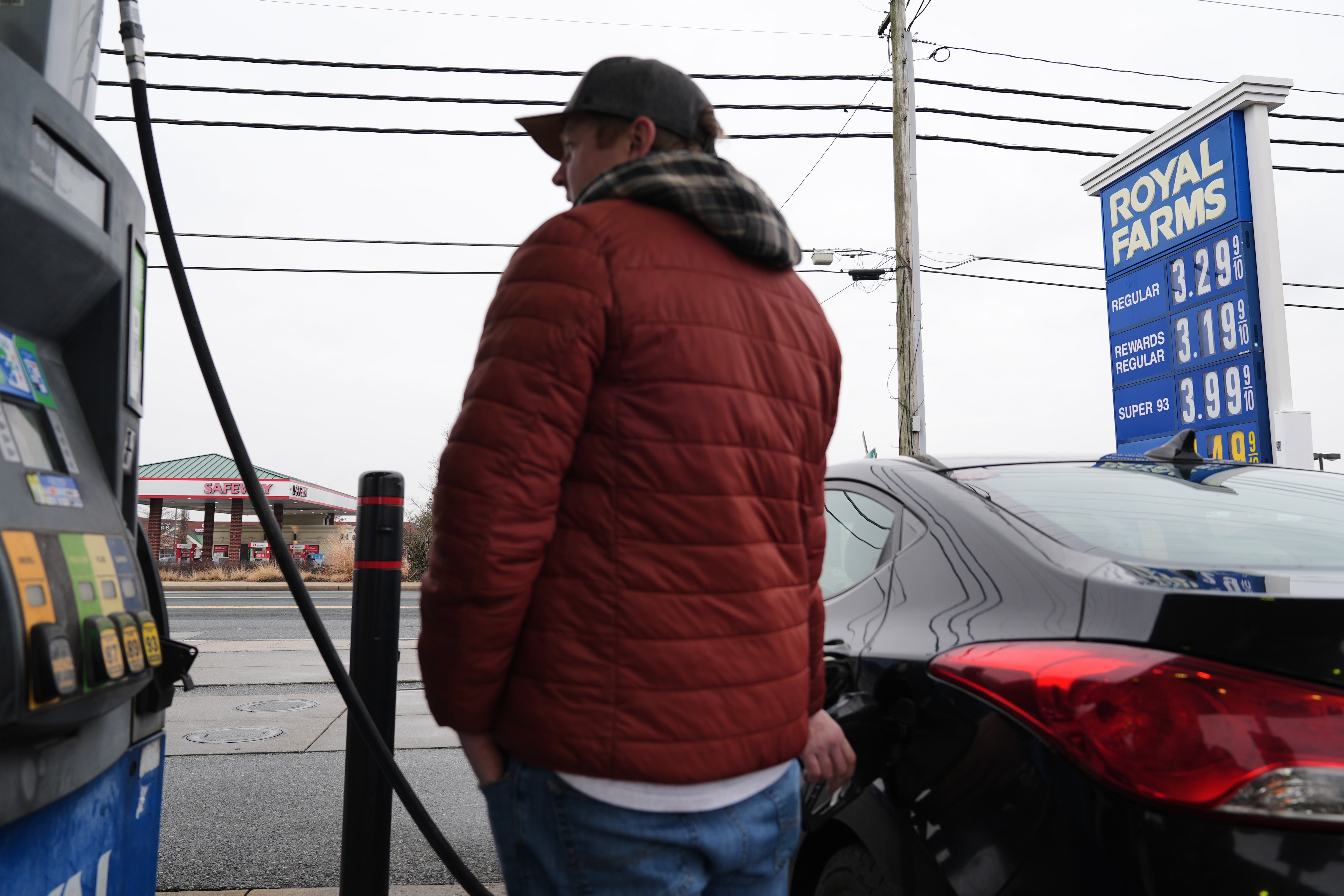 A person fills their car with gas as fuel prices at a gas station are displayed behind them, Wednesday, March 4, 2026, in Baltimore.