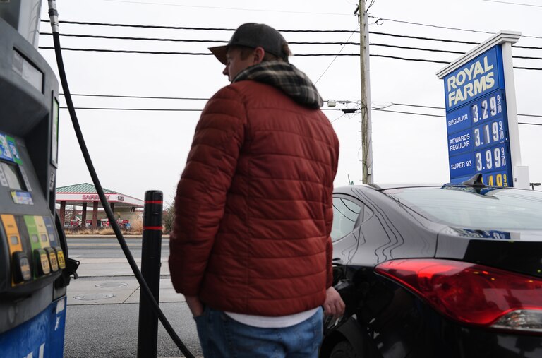 A person fills their car with gas as fuel prices at a gas station are displayed behind them, Wednesday, March 4, 2026, in Baltimore.