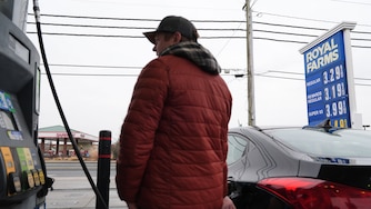 A person fills their car with gas as fuel prices at a gas station are displayed behind them, Wednesday, March 4, 2026, in Baltimore.