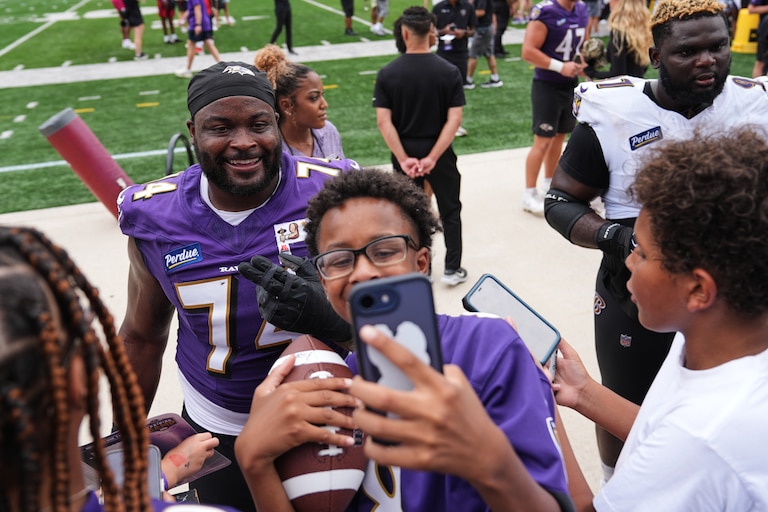 Baltimore Ravens guard John Simpson poses for a selfie with a fan during the team's NFL football training camp at the University of Maryland in College Park, Md., Saturday, Aug. 1, 2026. (AP Photo/Stephanie Scarbrough)