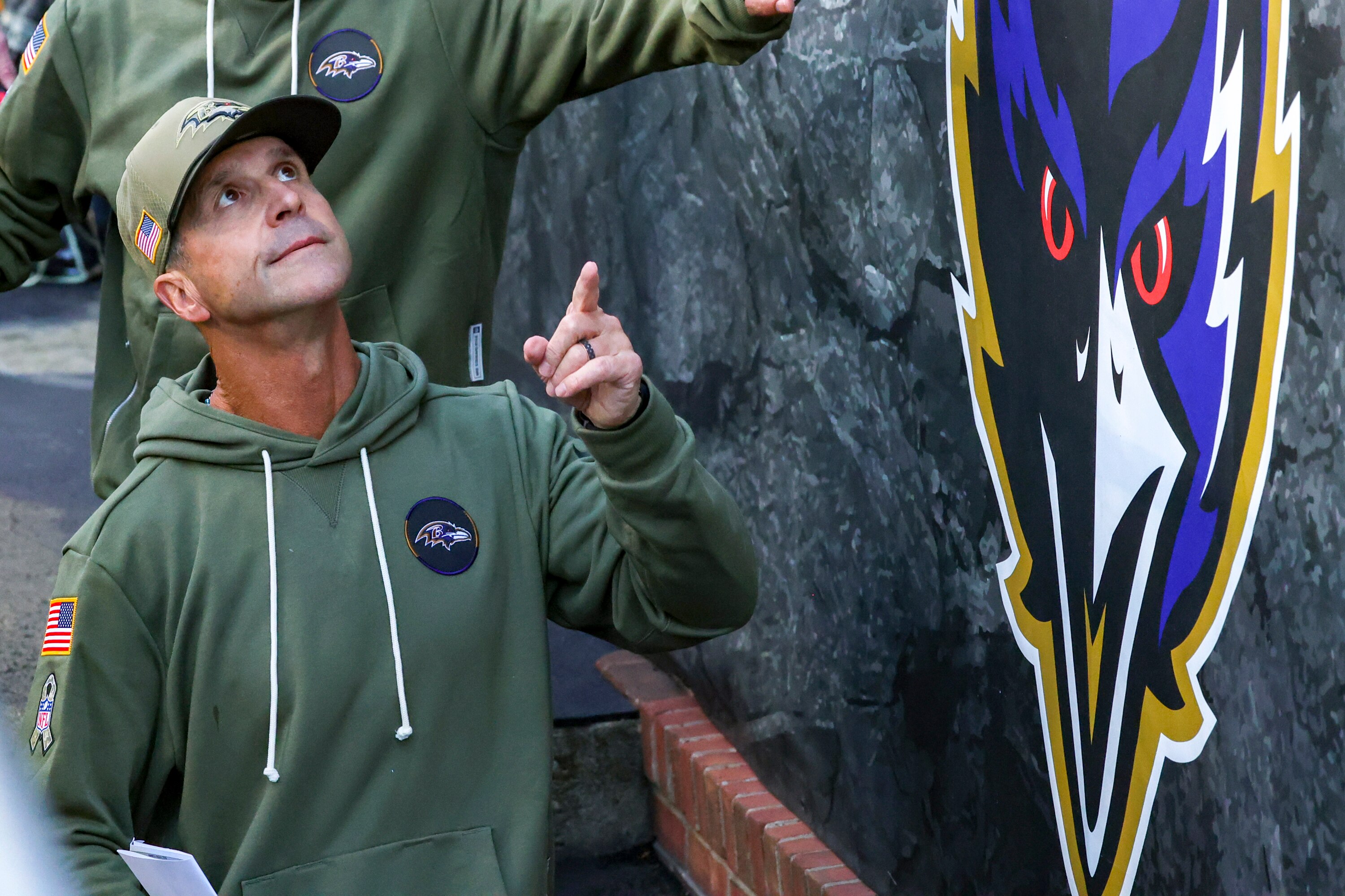 Baltimore Ravens head coach John Harbaugh acknowledges cheering fans as he exits the field after the Ravens victory over the Chicago Bears in 2025.