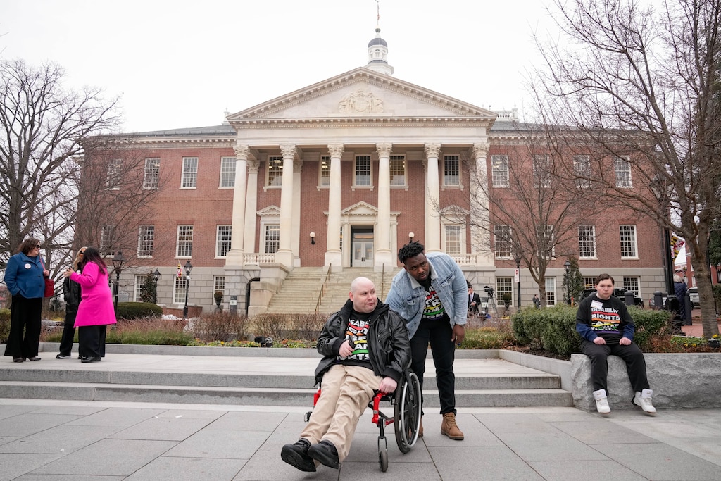 Mat Rice, executive director of People on the Go Maryland, center, accompanied by his direct service provider, Idris Paramole, following a rally held by the The Maryland Developmental Disabilities Coalition on Lawyers Mall in Annapolis, Md., on Wednesday, February 18, 2026.