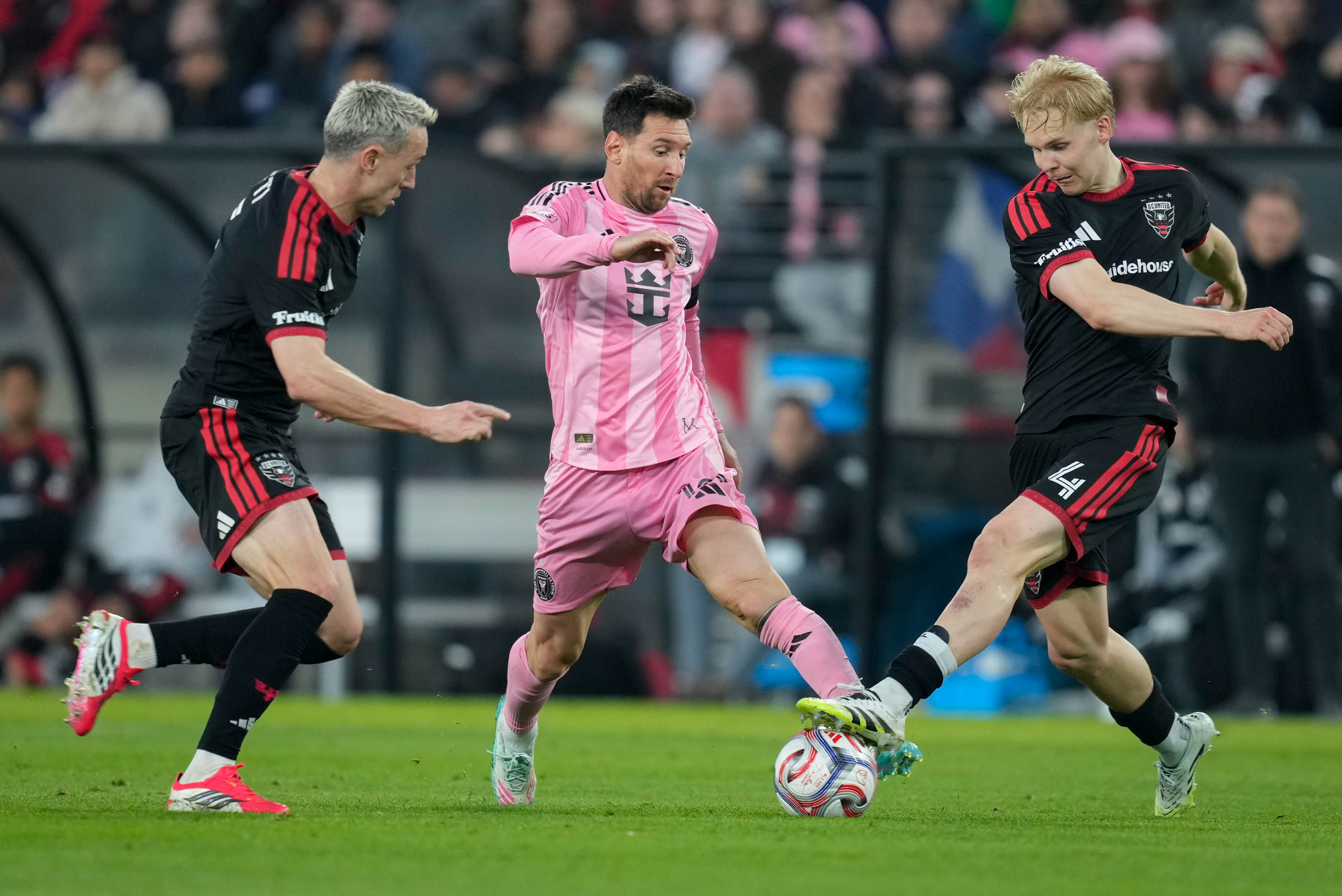 Inter Miami forward Lionel Messi fights for possession of the ball with two D.C. United defenders at M&T Bank Stadium on Saturday.