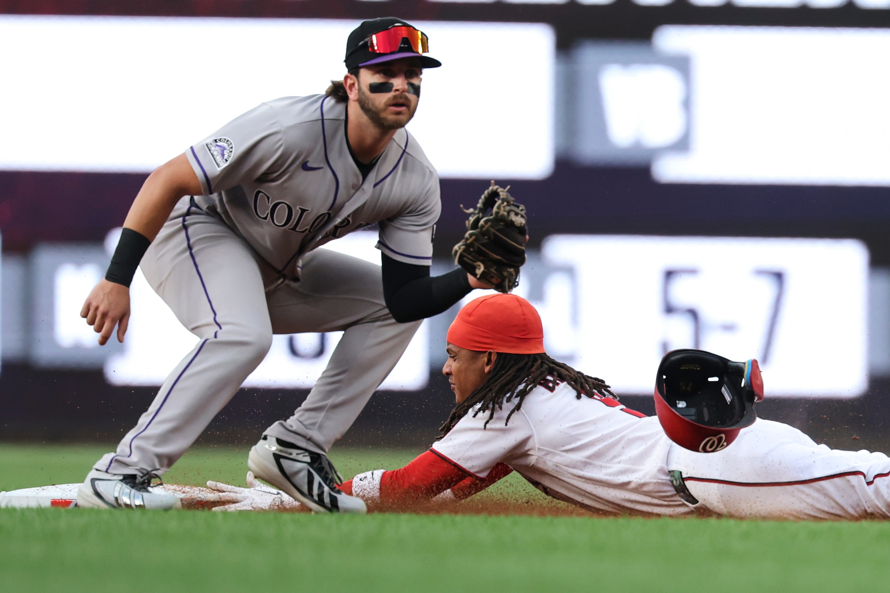 Washington Nationals' CJ Abrams, right, slides into second base for a steal during against the Colorado Rockies during the first inning.