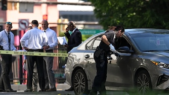 Baltimore County Police officers respond to a reported shooting that occurred along York Road in Towson on Friday afternoon. Bullet holes can be seen in the door of a vehicle.