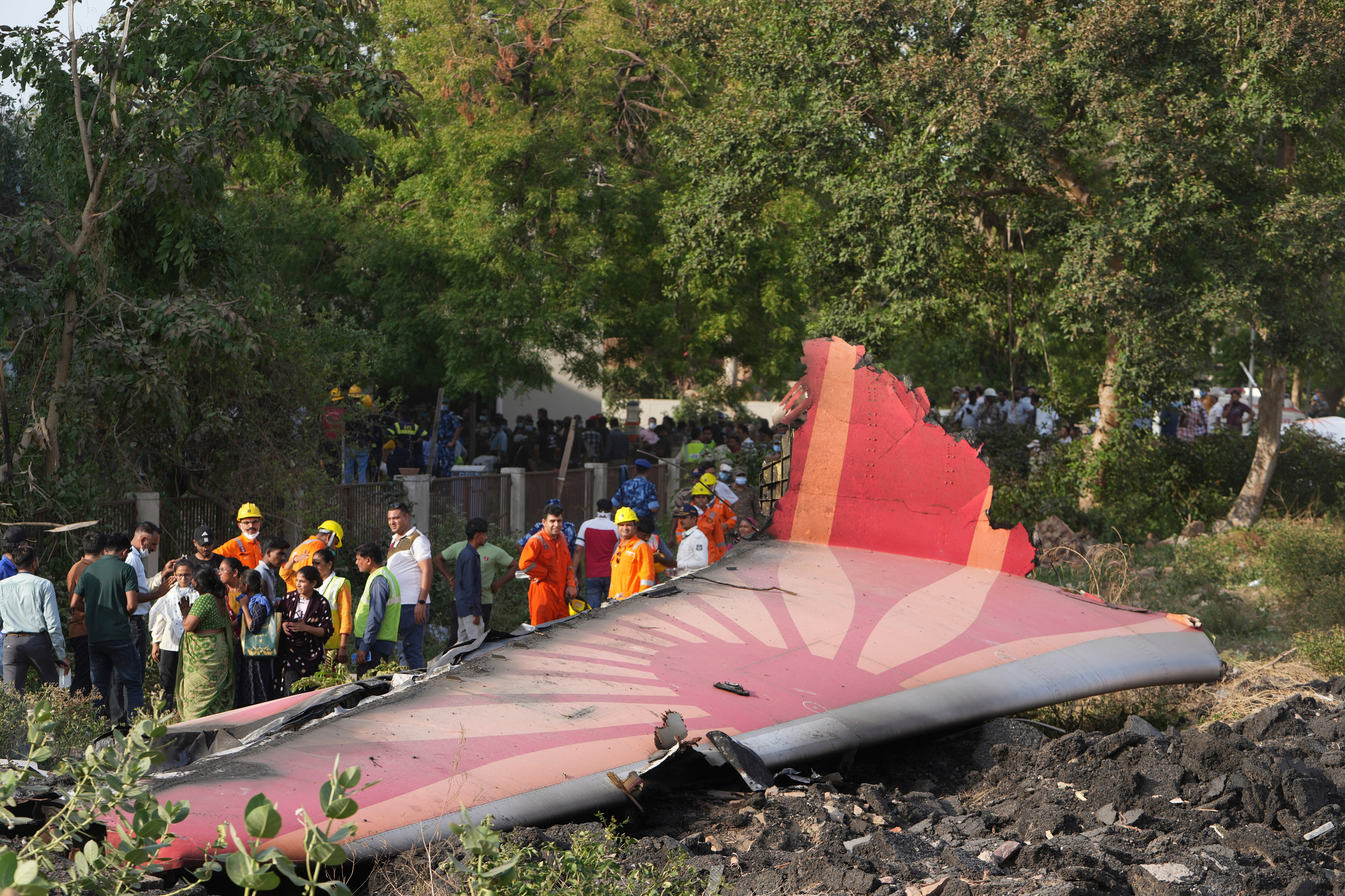 People stand around the debris of an airplane after it crashed in India's northwestern city of Ahmedabad in Gujarat state, Thursday, June 12, 2025. (AP Photo/Ajit Solanki)