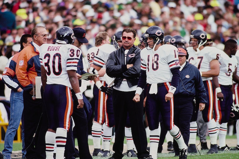 Mike Ditka, head coach for the Chicago Bears, looks on with arms folded from the sideline during the National Football Conference Central Division game against the Green Bay Packers on 16th September 1990 at Lambeau Field in Green Bay, Wisconsin, United States. The Chicago Bears won the game 31 - 13.