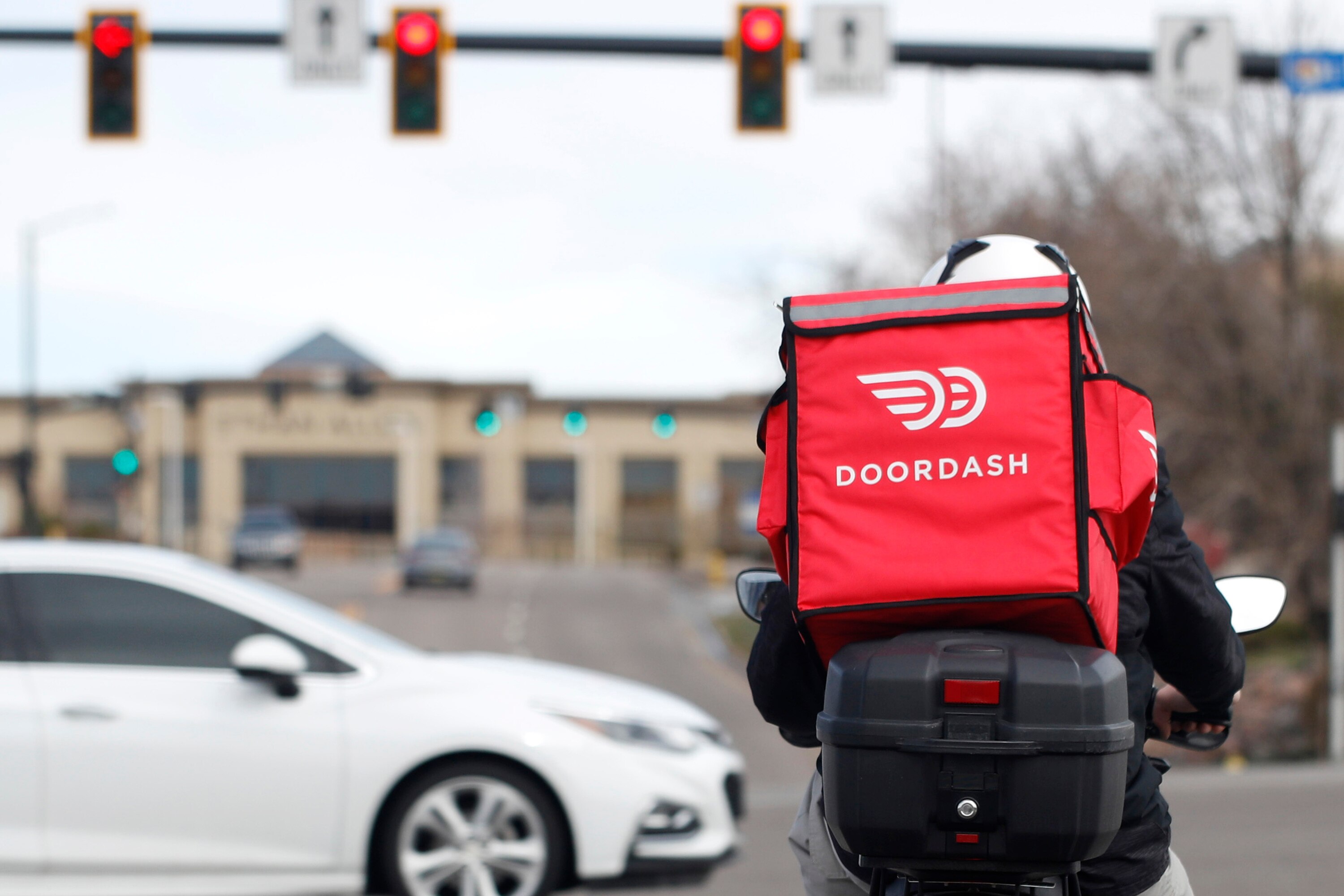 A food delivery motorcycle rider waits for the traffic light to change March 30, 2020, in Lone Tree, Colo.