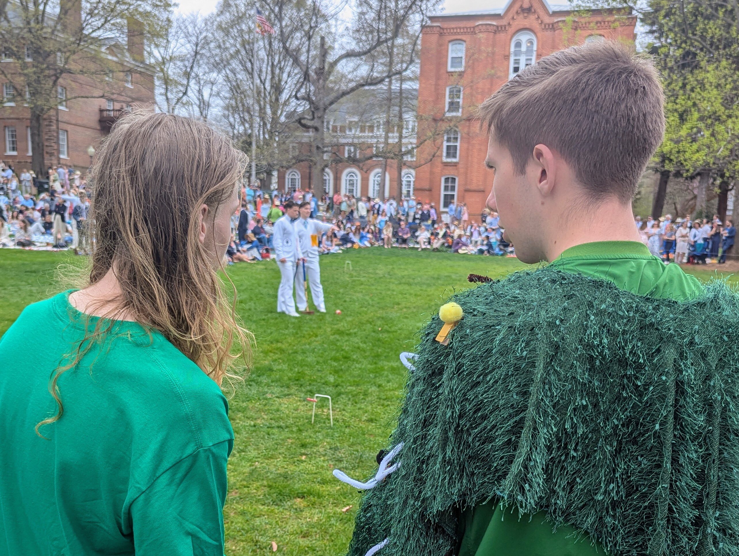 Two St. John's College students watch Naval Academy midshipmen prepare to take a shot in the Annapolis Cup croquet match Saturday.