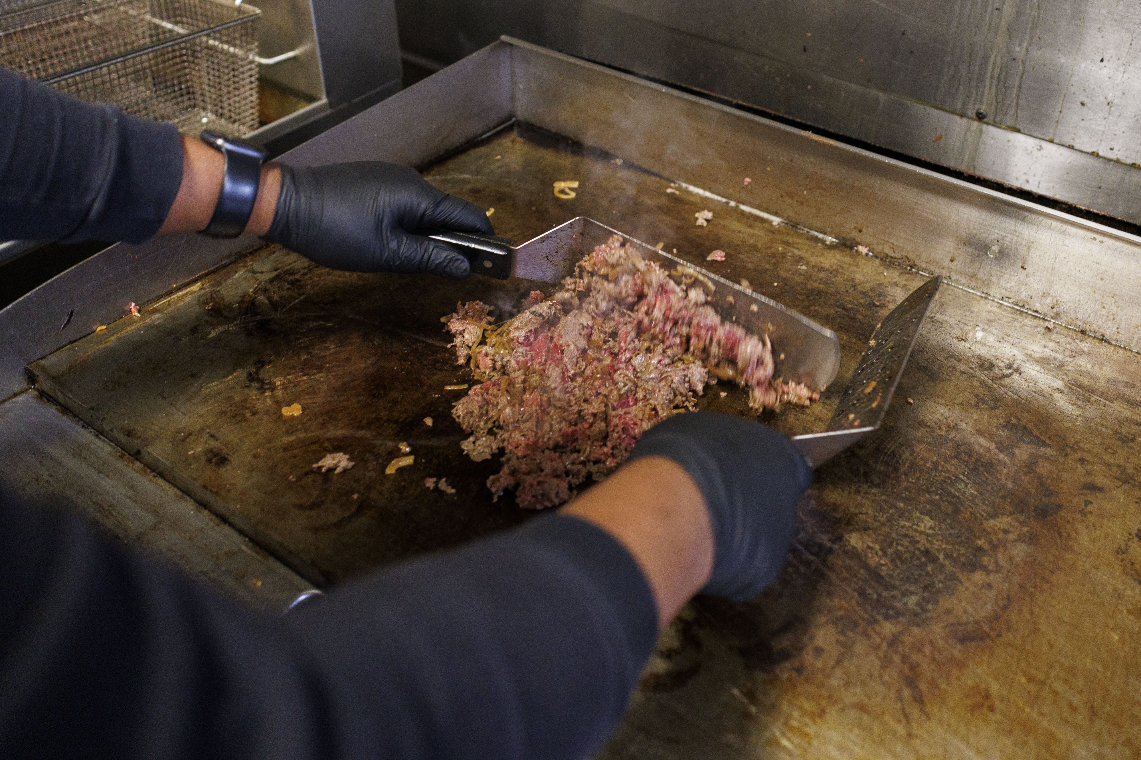 Armand Miles, co-owner of Dimples Bar & Grill in Locust Point, cooks steak for a cheesesteak. 