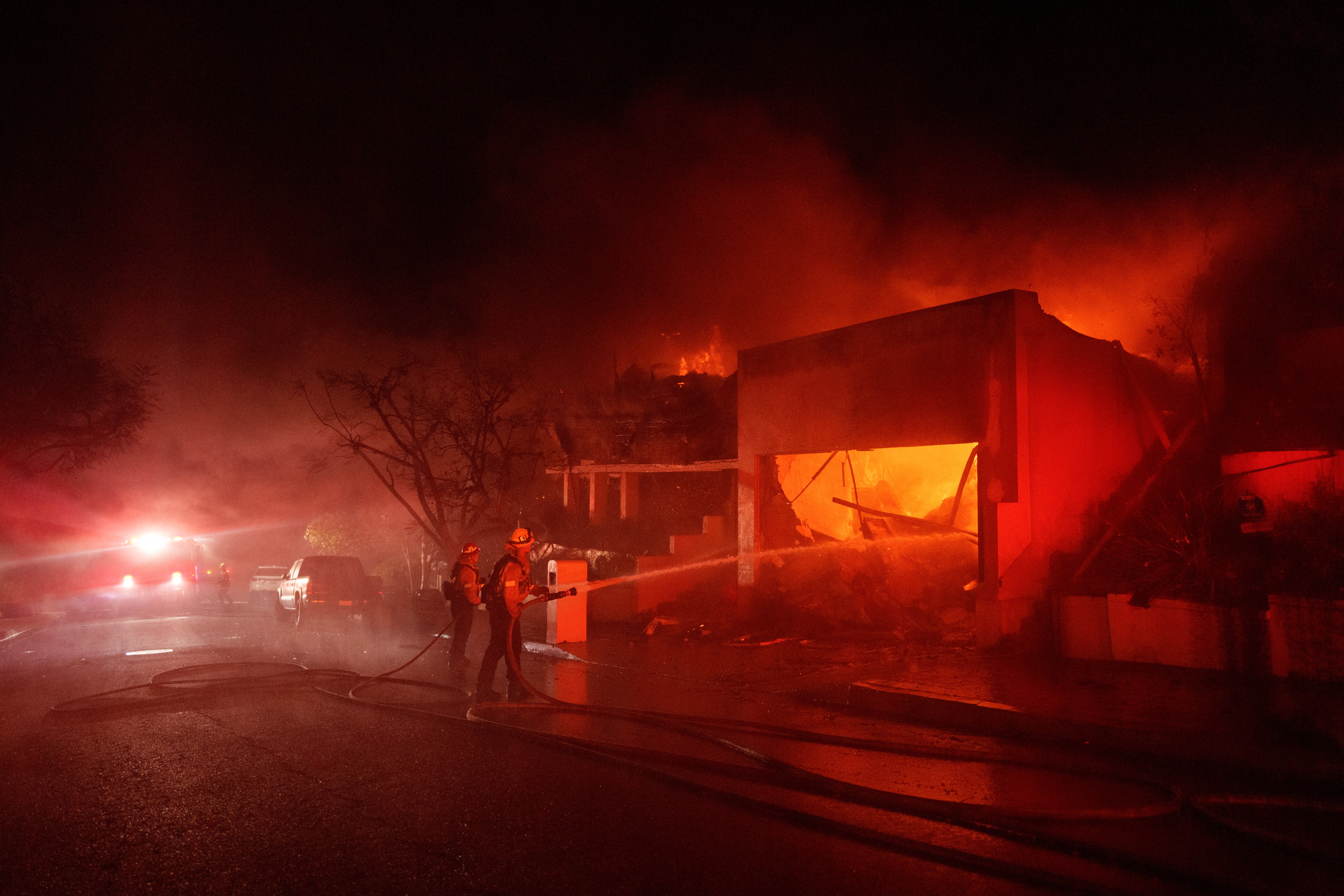 LOS ANGELES, CALIFORNIA - JANUARY 8: Firefighters battle flames from the Palisades Fire on January 8, 2025 in the Pacific Palisades neighborhood of Los Angeles, California.