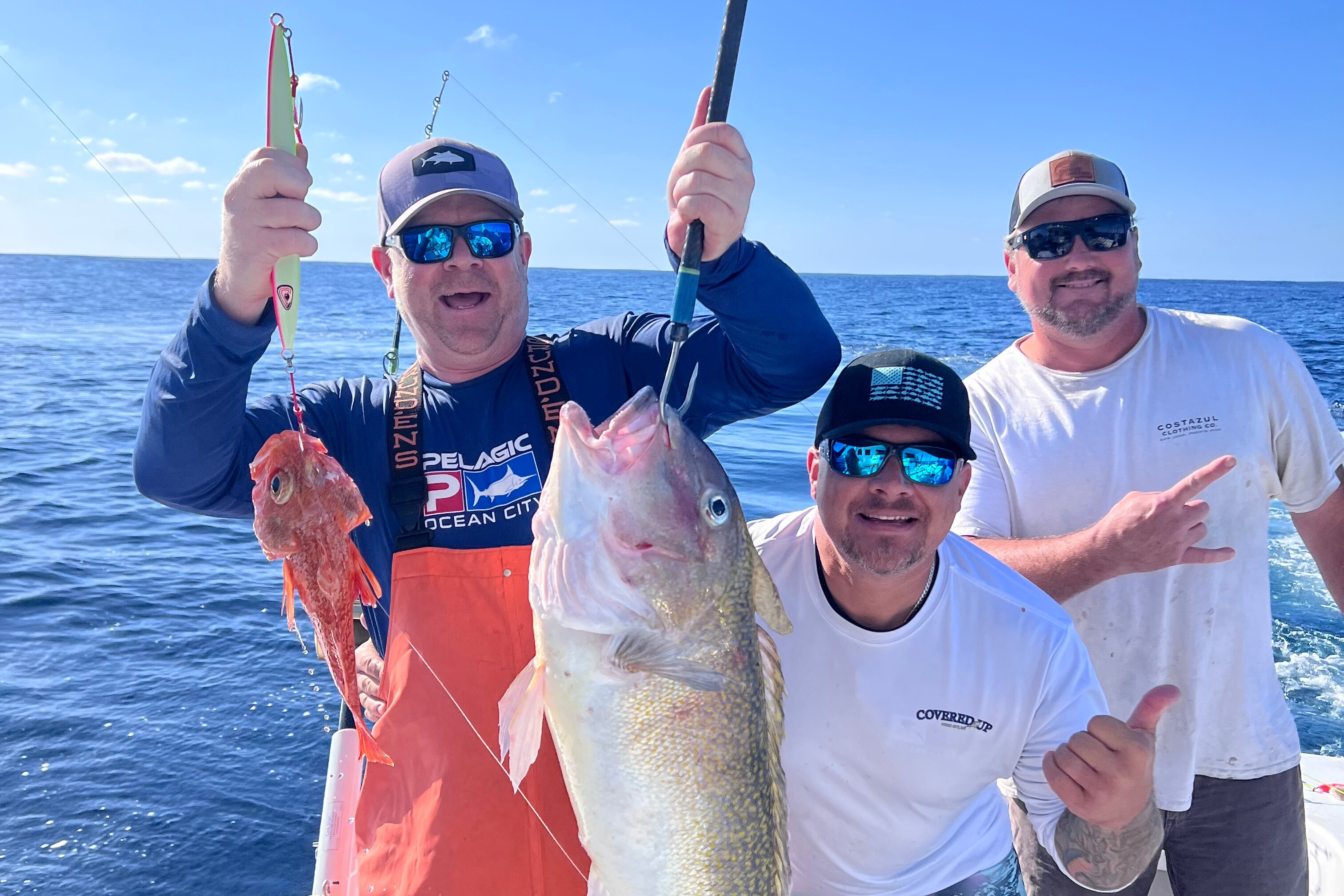 Three men on a boat with one of them holding up two fish