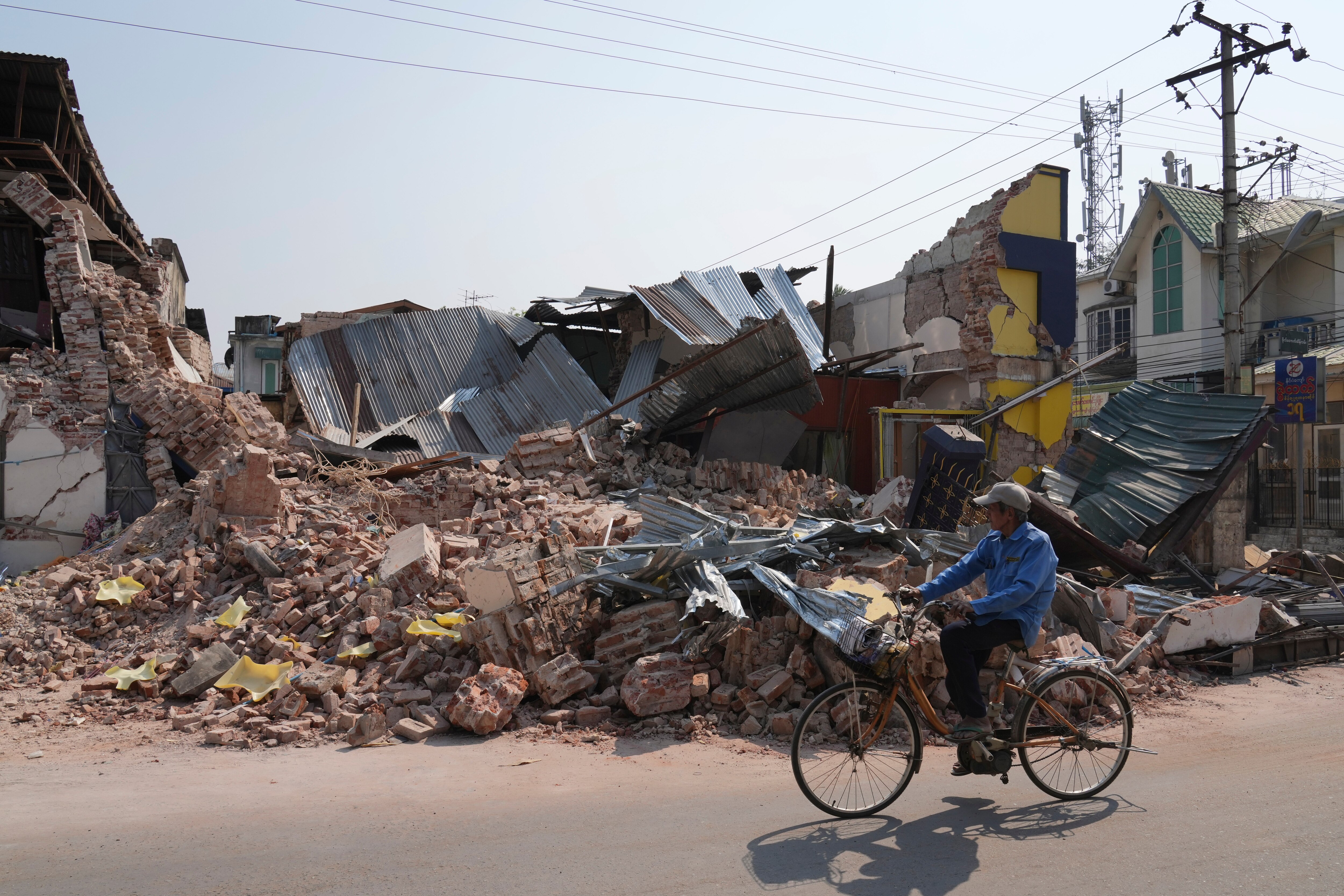 A local man rides a bicycle past a damaged building in the aftermath of an earthquake, in Naypyitaw, Myanmar on Sunday.
