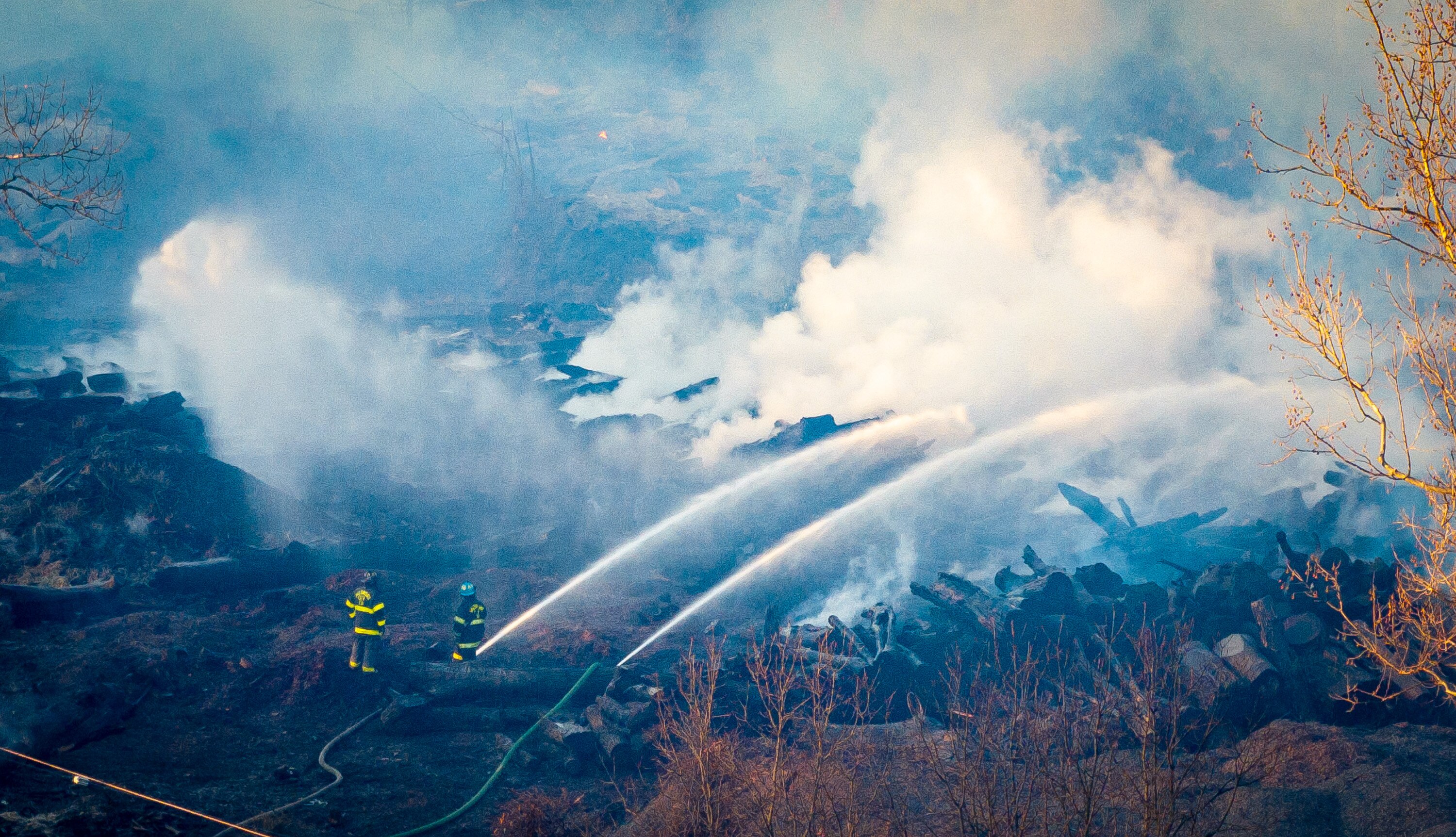 Firefighters spray water on the smoldering wood piles as fire continues to burn at the Camp Small city wood recycling facility in December.