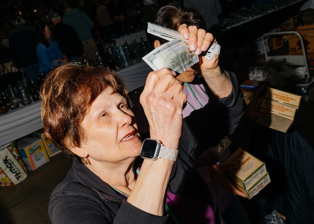 Gloria Kim of Strongstown, PA, holds up $100 bills to the light after making a $1100 sale at The Baltimore Antique Bottle Club 45th Annual Show & Sale at the Howard County Fair Grounds