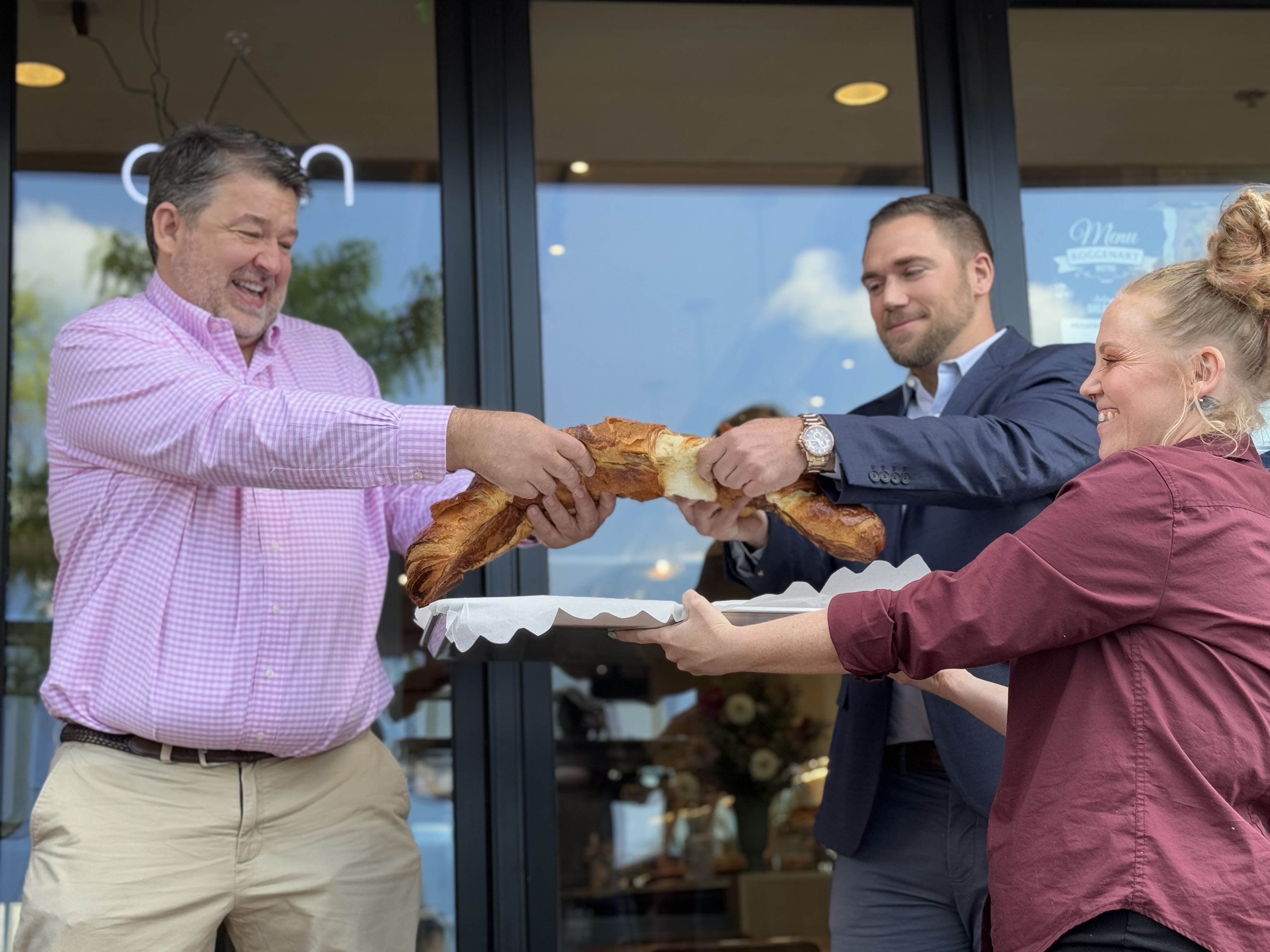 Neman Popov, the founder of Roggenart European Bakery, Bistro and Cafe, left, splits a very large croissant with owner and partner Brody Tennant outside the City House Charles office complex.