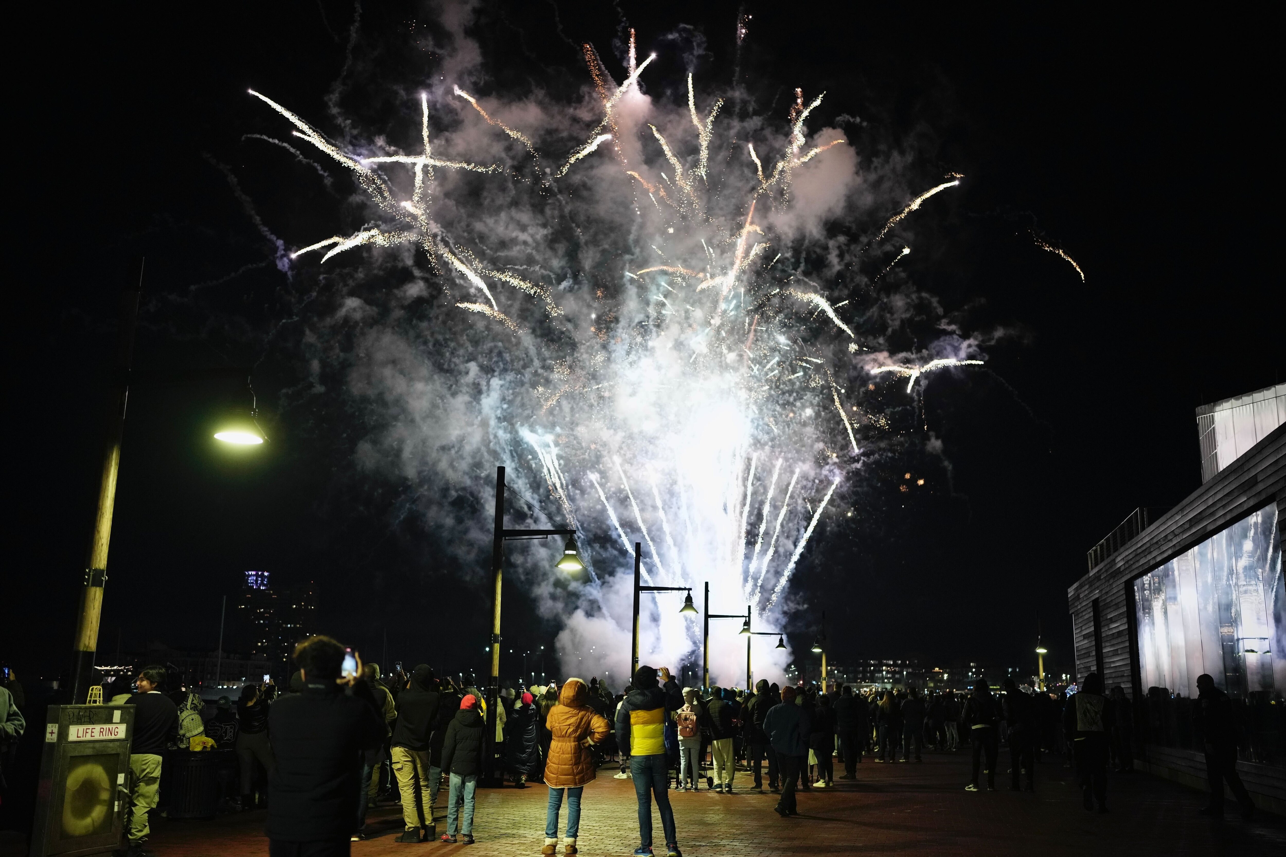 People enjoy the fireworks show by the Inner Harbor to ring in the new year in Baltimore on January 1, 2025.
