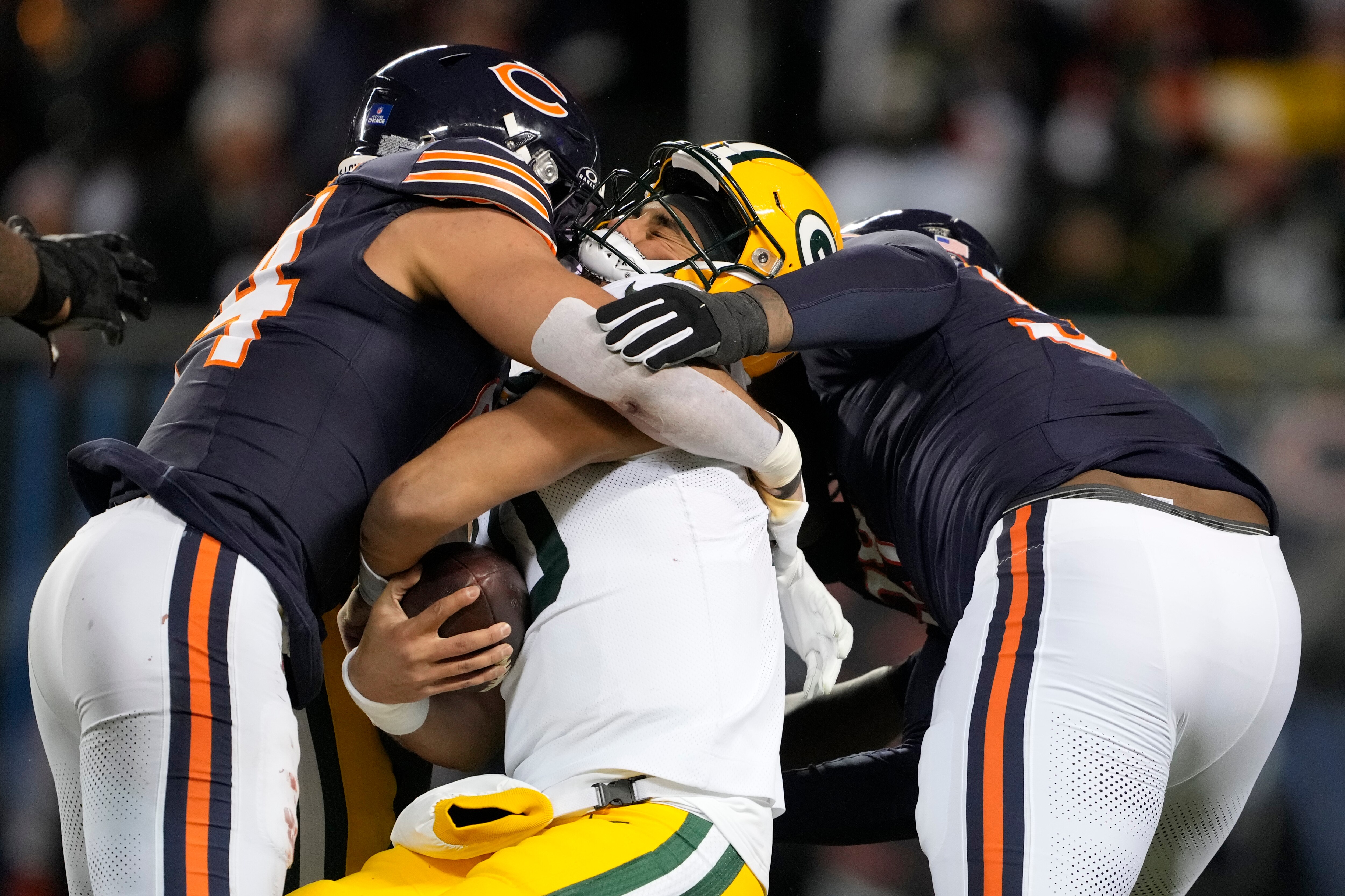 Jordan Love of the Packers takes hits from Austin Booker, left, and Gervon Dexter Sr. of the Bears during the second quarter Saturday night.