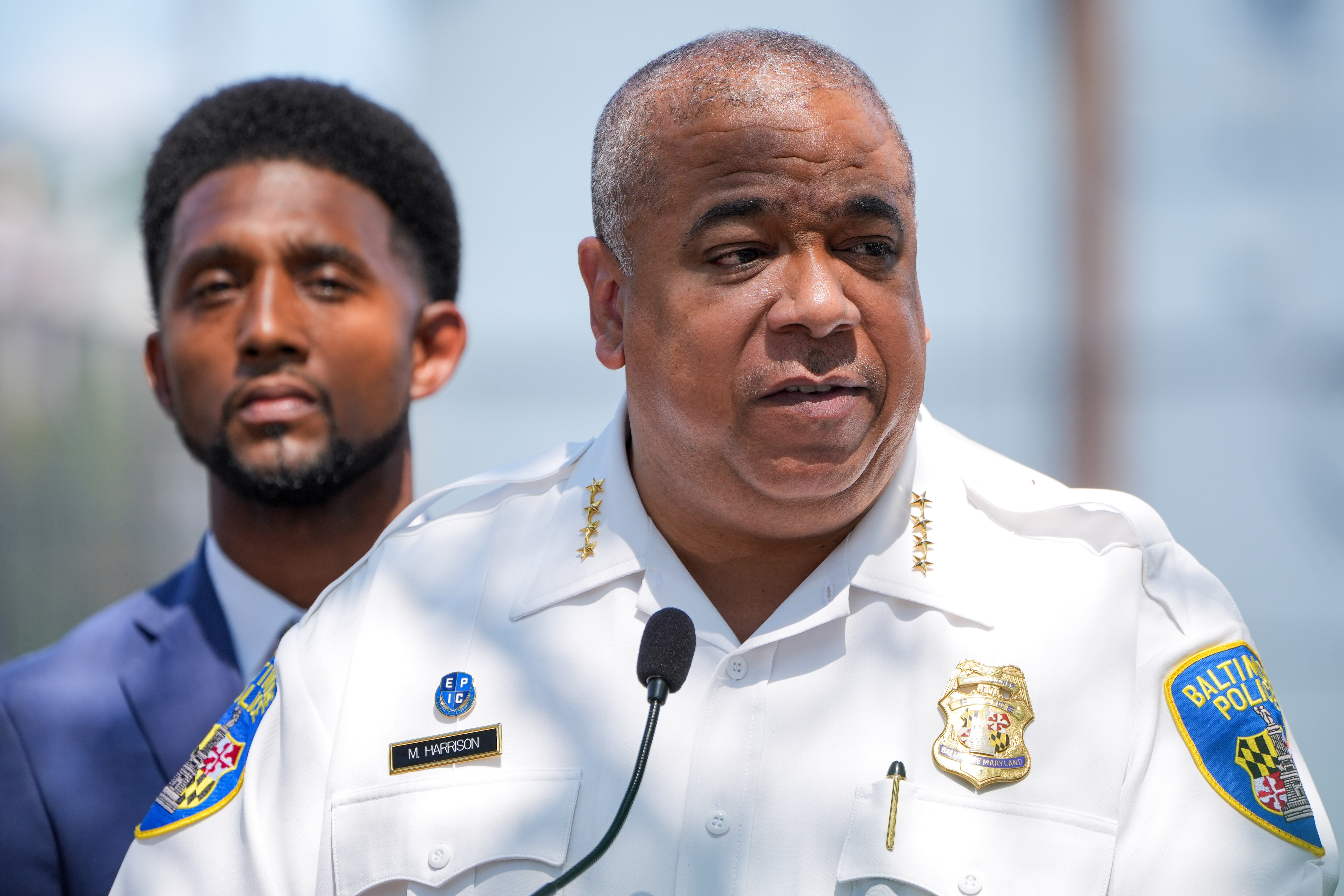 Baltimore Police Commissioner Michael Harrison, flanked by Mayor Brandon Scott, speaks at a press conference outside Tench Tilghman Elementary/Middle School to highlight resources and initiatives meant to reduce violent crime in Baltimore on Aug. 24, 2022.