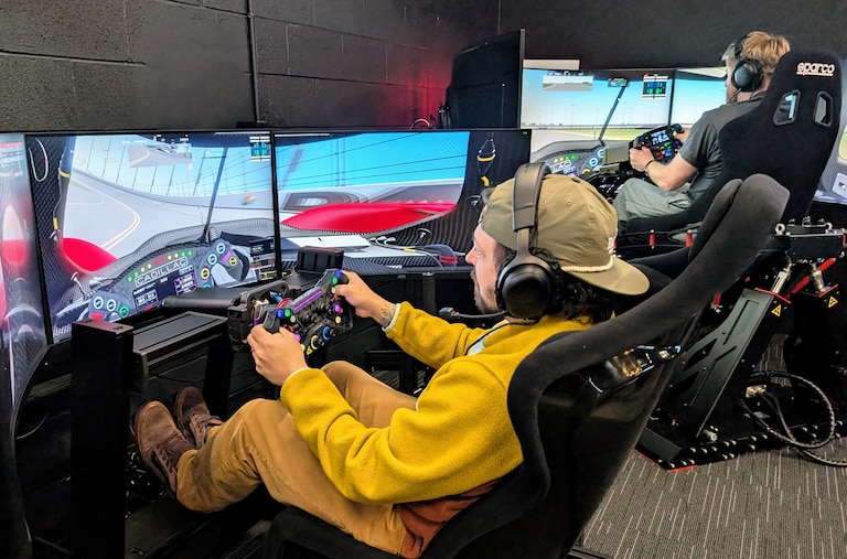 Bryce Swarm, left, and JP Dwyer run a demonstration race in two of the cockpits at PS1 Sim Racing Annapolis. The rigs rely on a computer physics generator to match the use of steering wheels and pedals to images on the screen, sounds and motions.