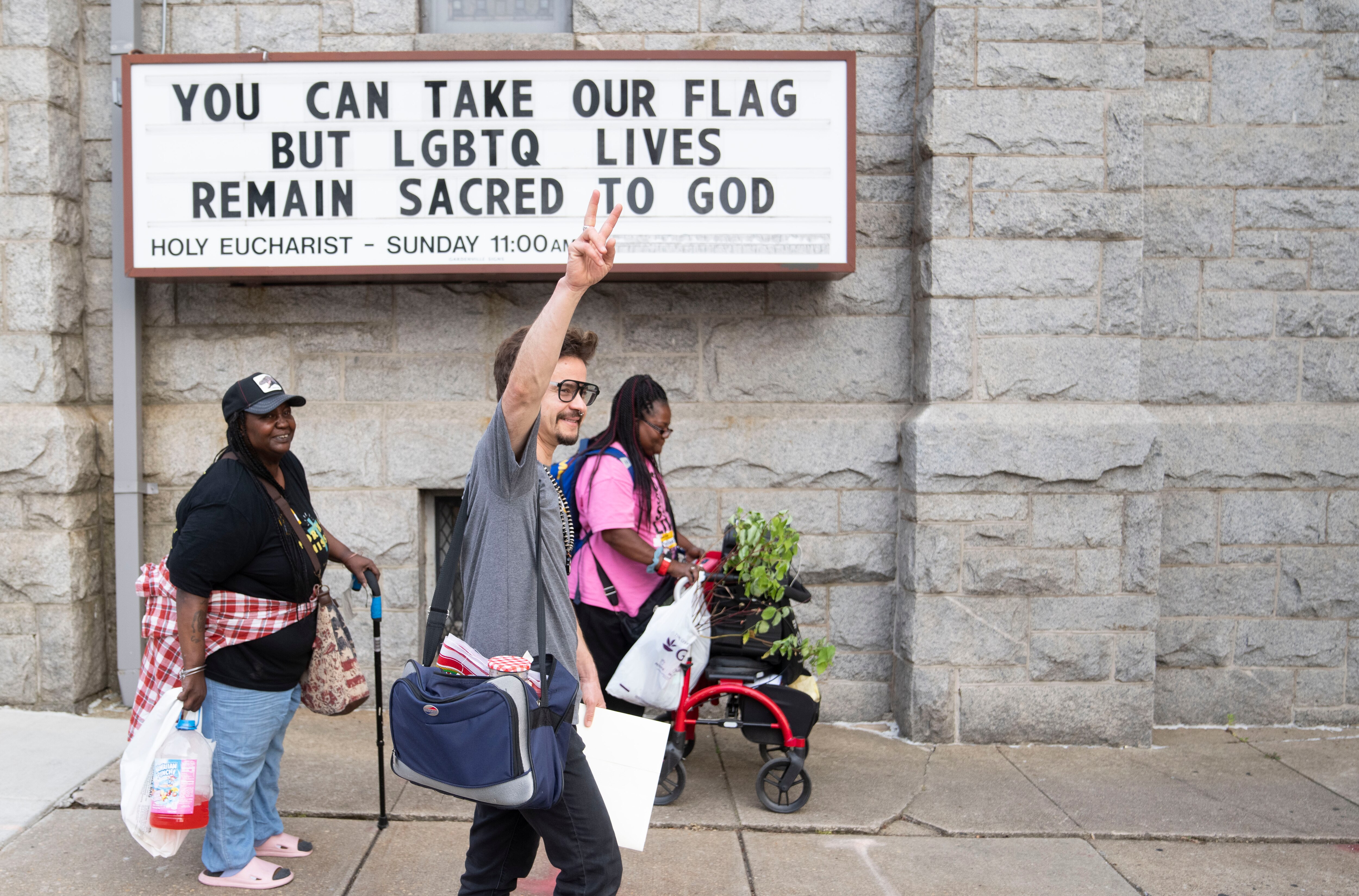 Rev. Elazar Atticus Schoch Zavaletta waves to those passing across the street after holding a meeting for those of North Ave Mission at St Mark's Lutheran Church, Tuesday, June 6, 2023.