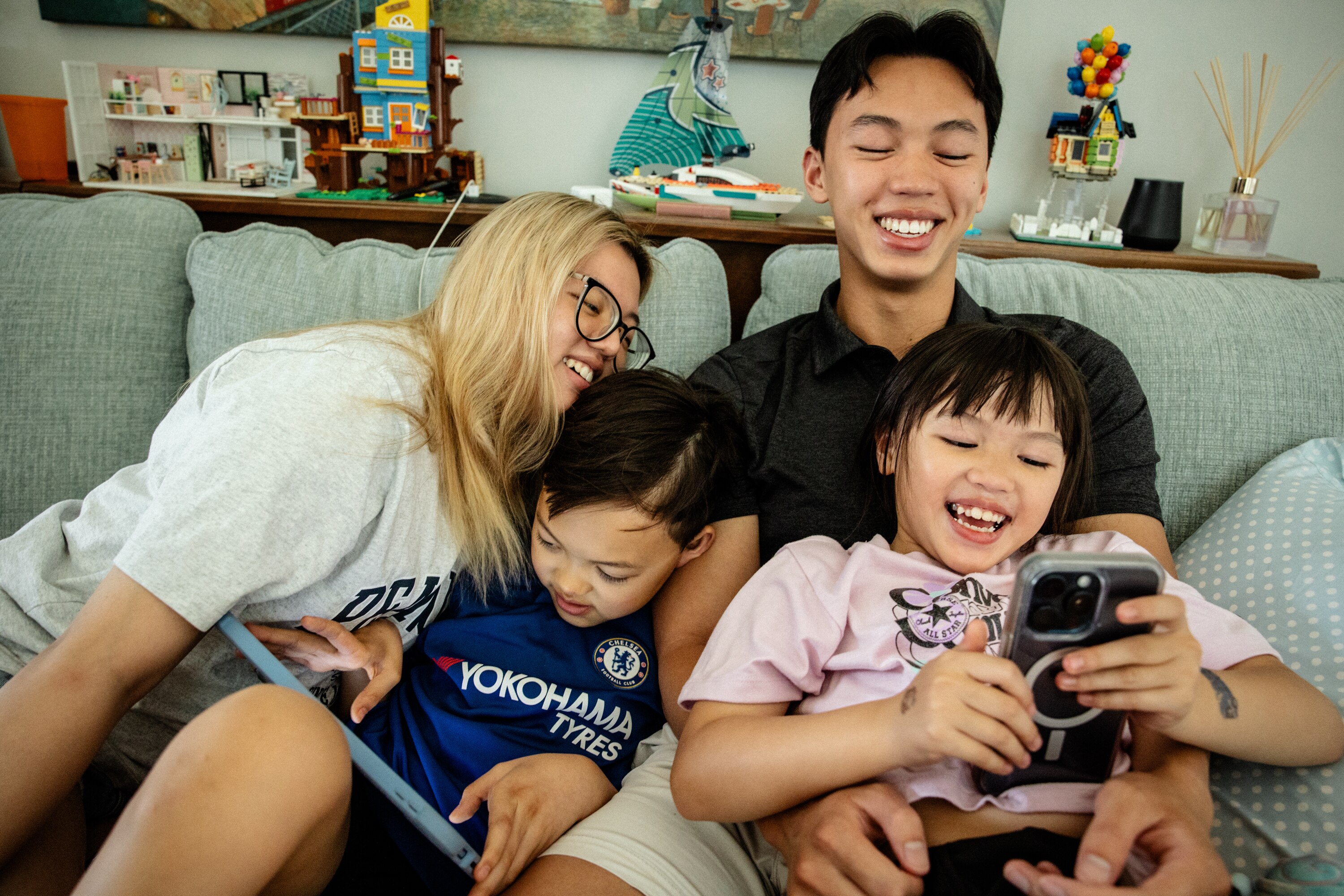 Siblings, Rachel, 18, Jacob, 10, Jackson, 19, and Riley Hoang, 6, spend time together and play with Snapchat filters on their living room couch on June 4, 2025.