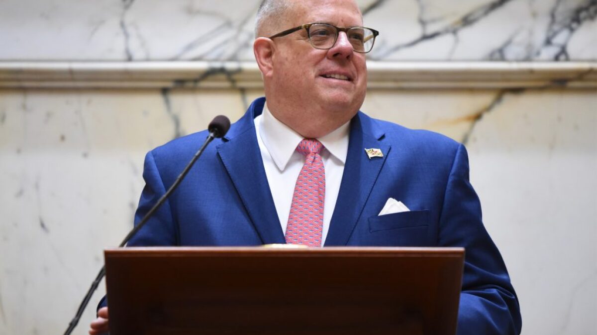 Governor Larry Hogan stands in front of a dais and microphone.