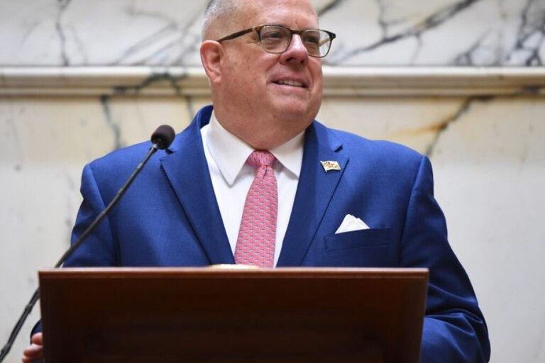 Governor Larry Hogan stands in front of a dais and microphone.