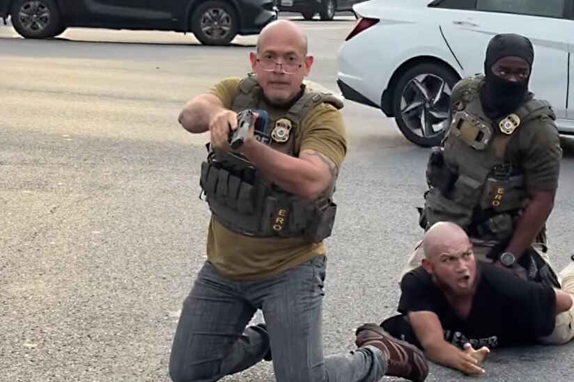 An ICE officer points a gun toward bystanders during an arrest on Wednesday in Hyattsville.
