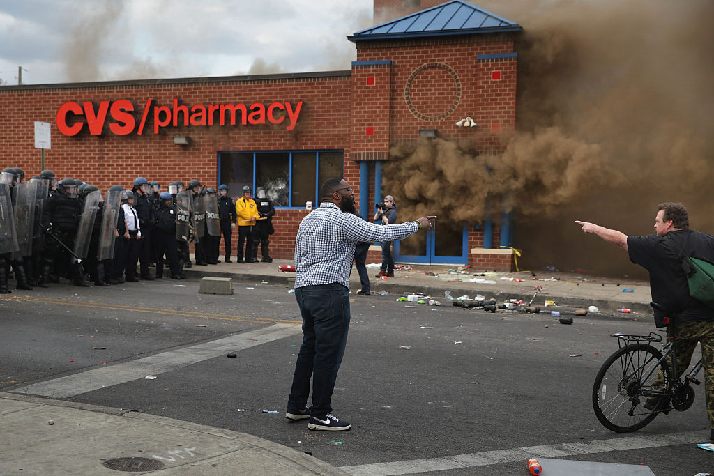 BALTIMORE, MD - APRIL 27: Two men argue opposing views as a CVS pharmacy burns at the corner of Pennsylvania and North avenues during violent protests following the funeral of Freddie Gray April 27, 2015 in Baltimore, Maryland. Gray, 25, who was arrested for possessing a switch blade knife April 12 outside the Gilmor Homes housing project on Baltimore's west side. According to his attorney, Gray died a week later in the hospital from a severe spinal cord injury he received while in police custody.