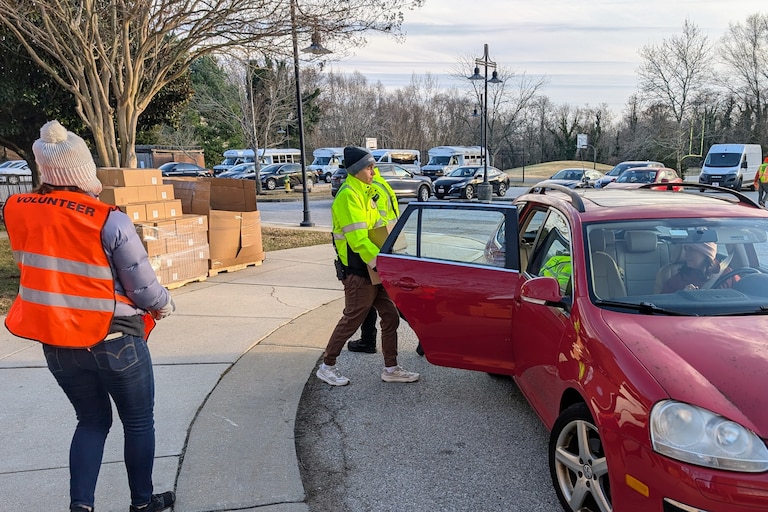 Volunteers put canned goods and fresh produce into the backseat of a car at a food relief distribution on Dec. 4, 2025 in Annapolis.
