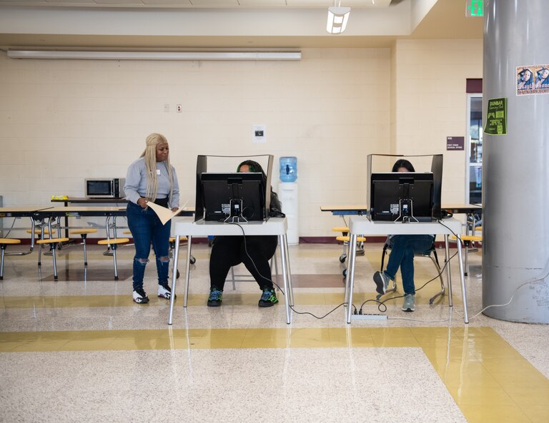 Voters use the ballot marking devices on Nov. 8, 2022 at Dunbar High School in Baltimore. Election judge Joana Pate instructs voters as they complete their ballots.
