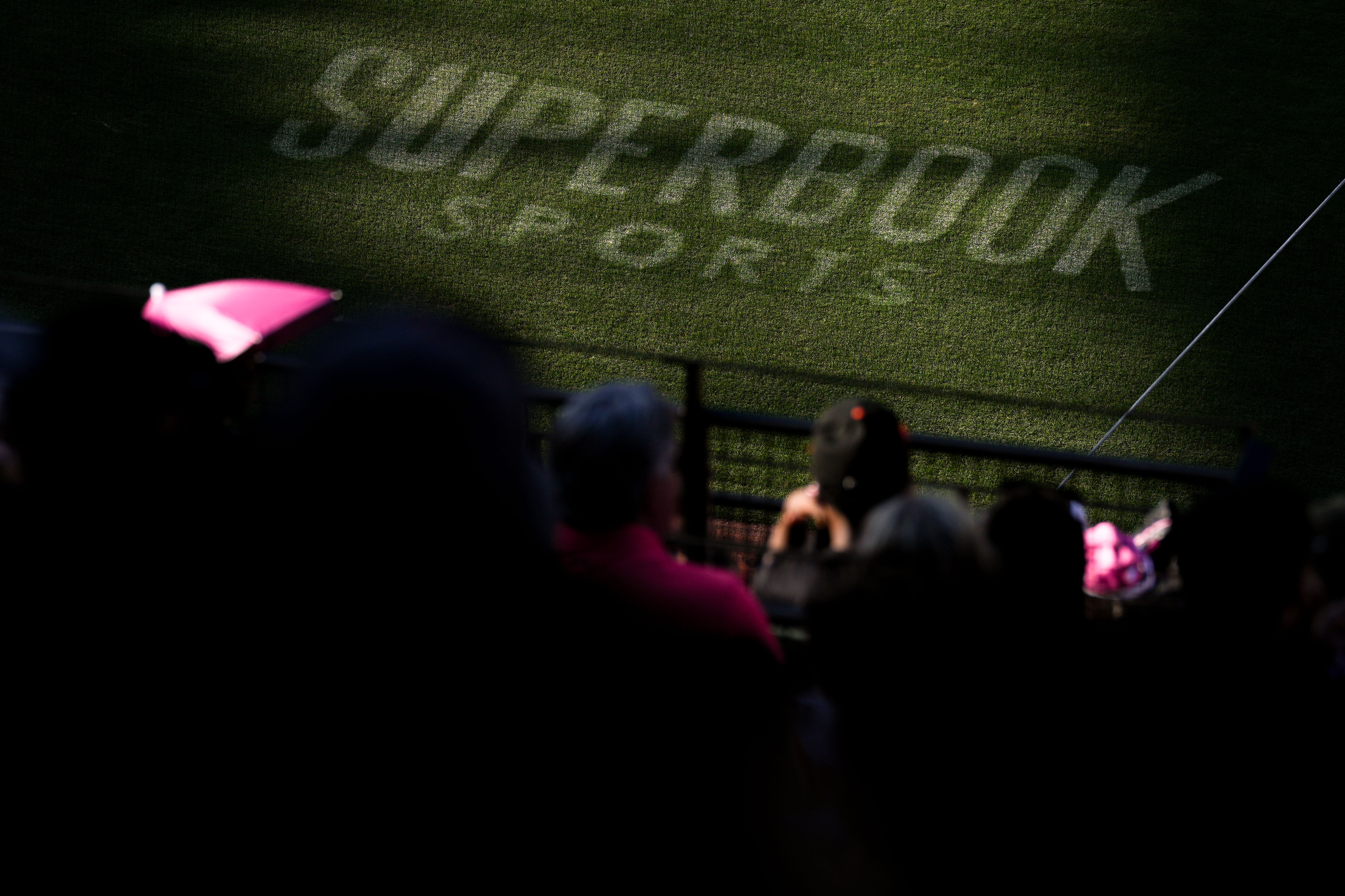 A SuperBook Sports logo on the field is highlighted by the setting sun during an Orioles game.