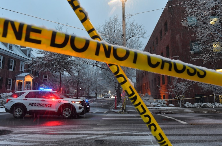 A police vehicle rests at an intersection near crime scene tape at Brown University.
