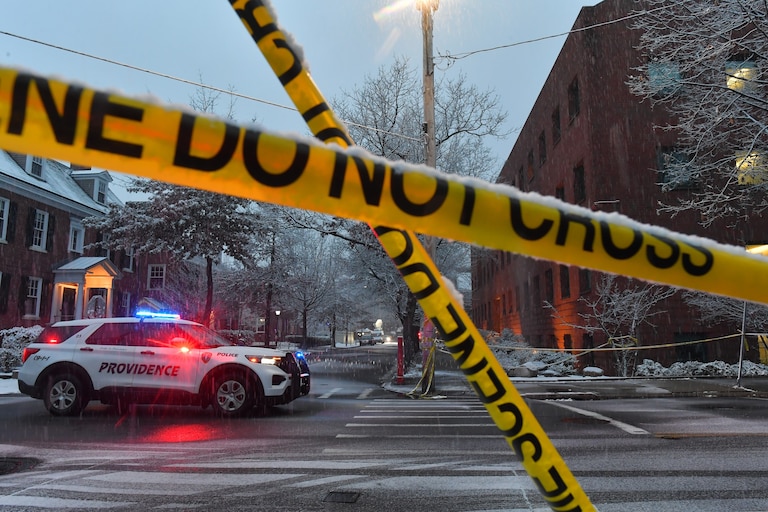 A police vehicle rests at an intersection near crime scene tape at Brown University.