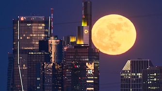 The full moon rises behind the buildings of the banking district in Frankfurt, Germany, Friday, May 1, 2026. (AP Photo/Michael Probst)