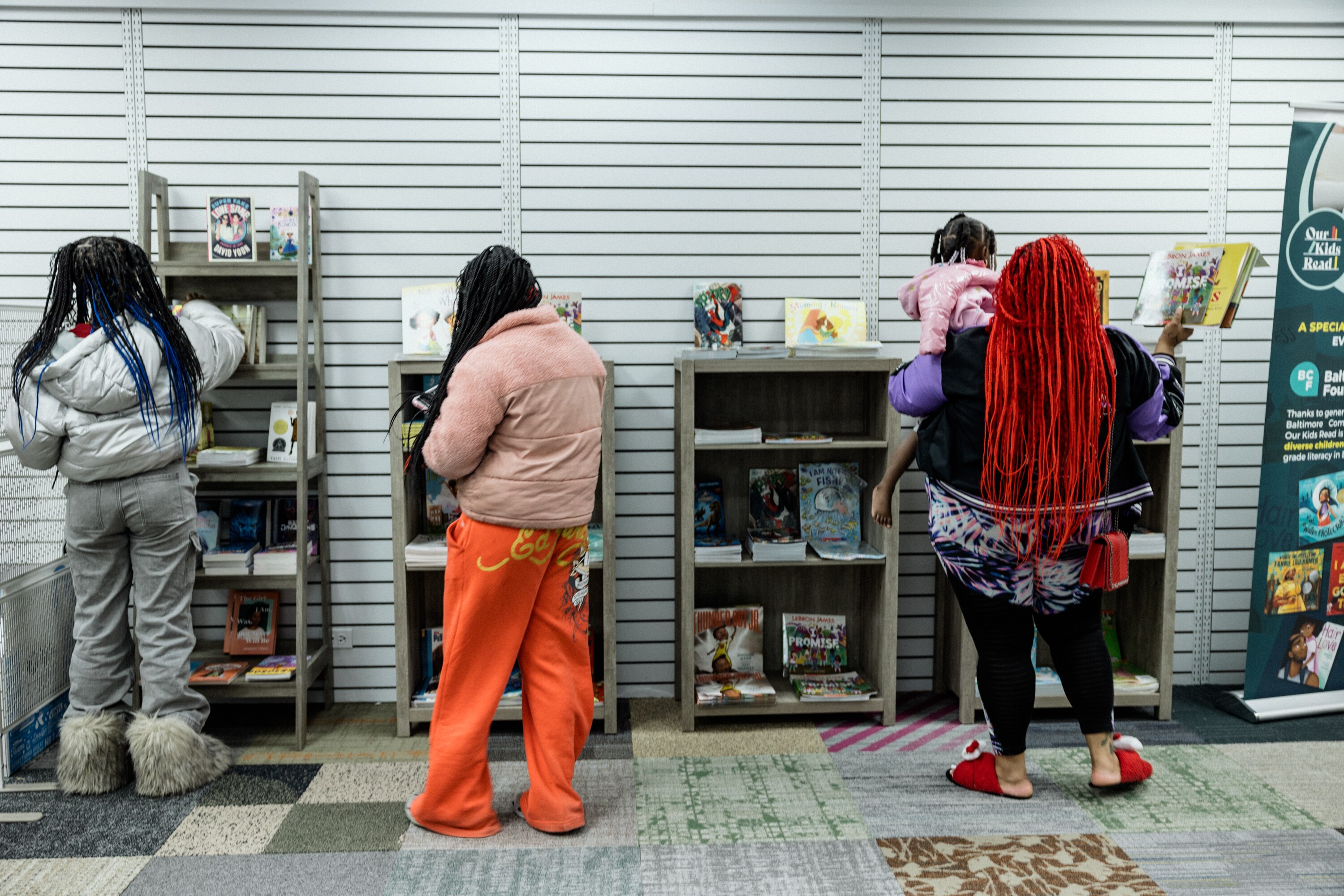 Ashley Johnson, right, and her children pick out books at the Our Kids Read Baltimore Literacy Hub, which offers three free books to every kid who walks in the door.