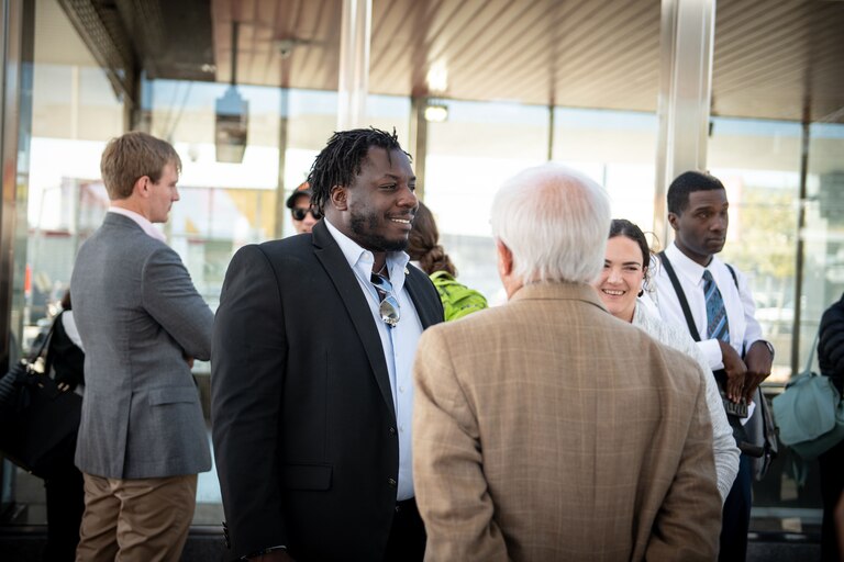 State Delegate Malcolm Ruff smiles and stands with a group of other adults outside a transit stop.