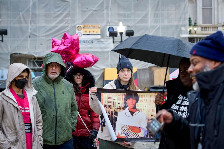 Loved ones and supporters of Donnell Rochester stand in the rain at a memorial vigil on the anniversary of his death. Rochester was killed by police on February 19, 2022.