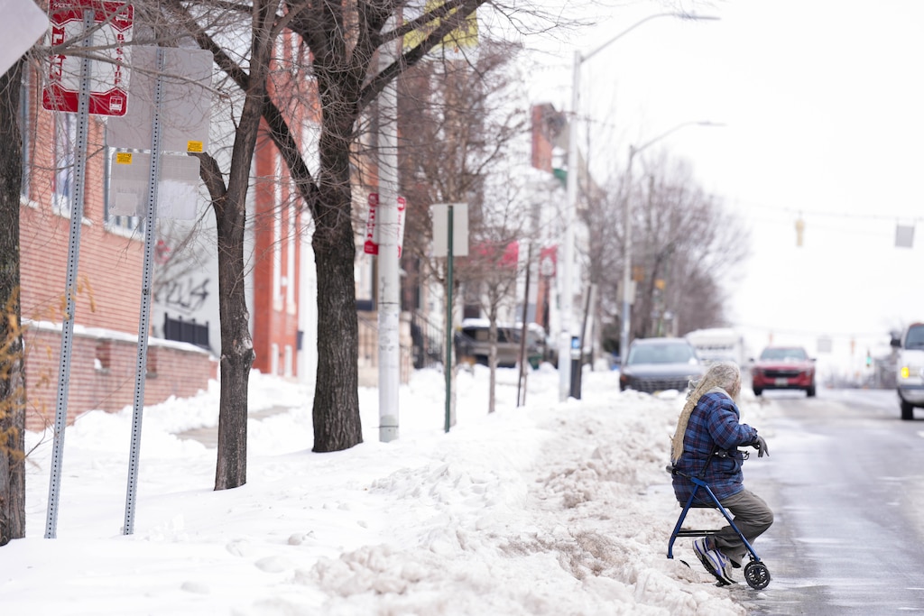 A man sits in a rolling walker as he waits for the bus to arrive on 25th Street in the aftermath of a snowstorm in Baltimore, Md., on Wednesday, January 28, 2026.