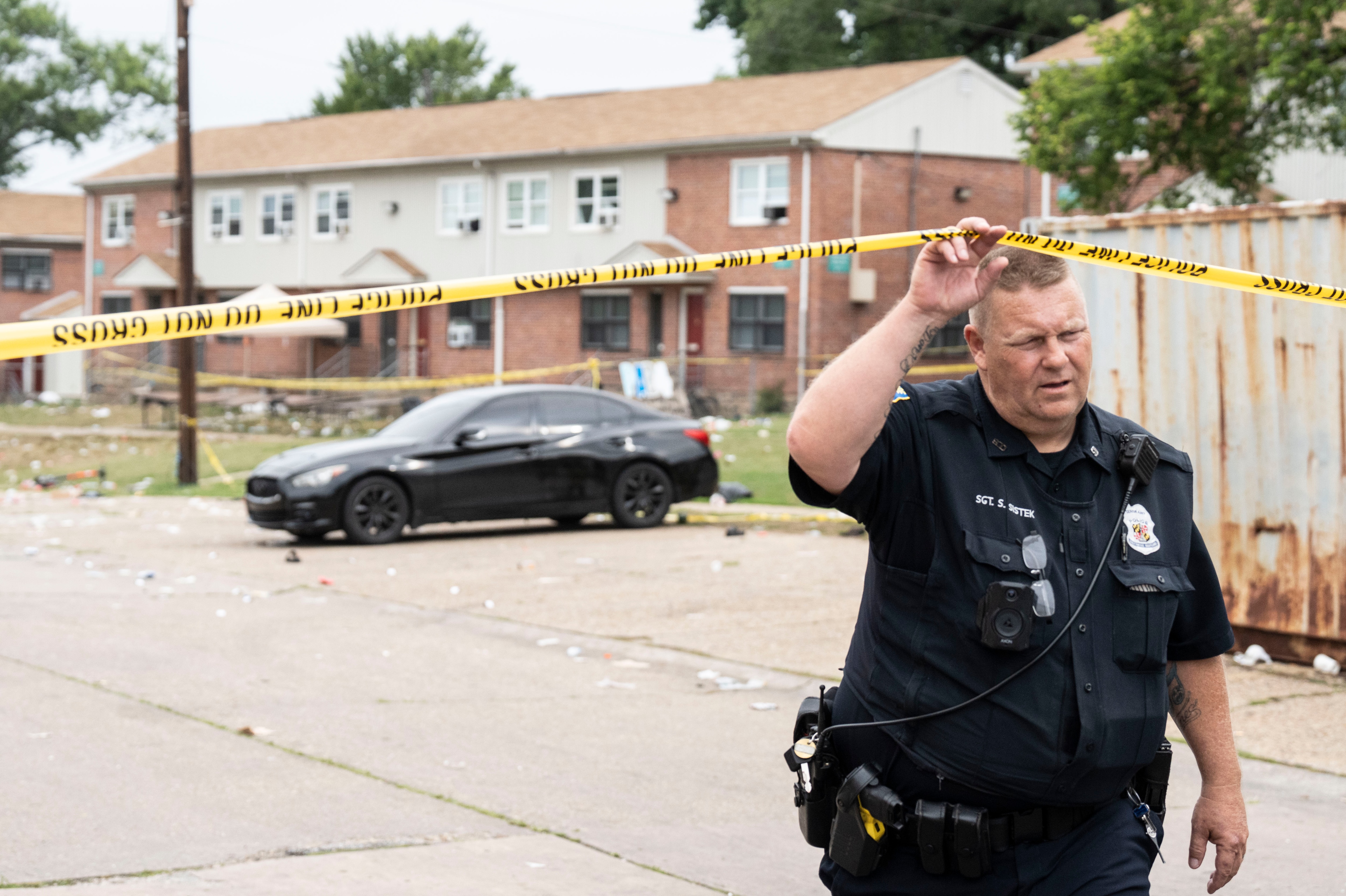A police officer goes under tape that marks off Glade Court in Brooklyn after a shooting early Sunday morning.