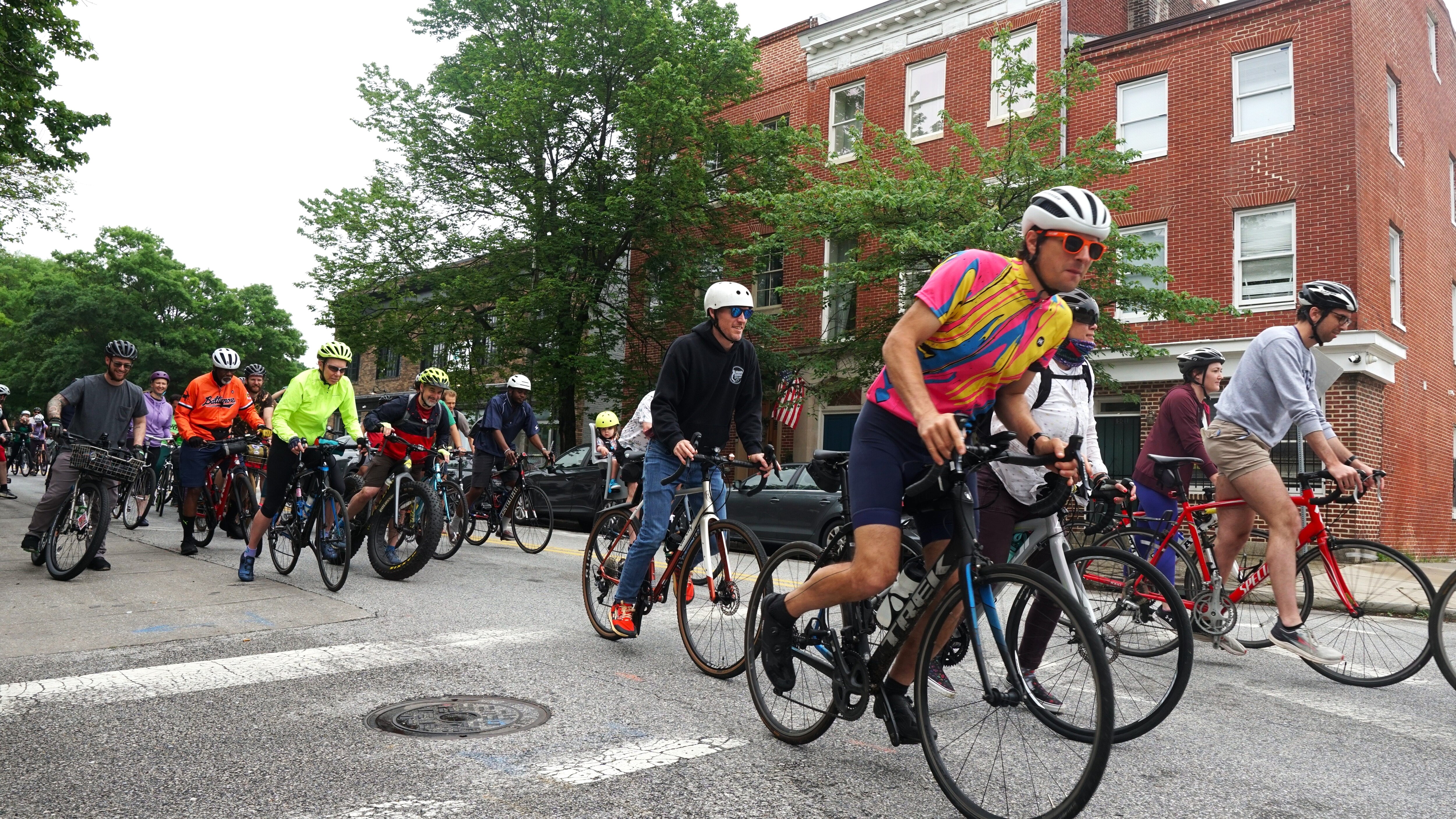 A group of cyclists bike left to right down a city street.