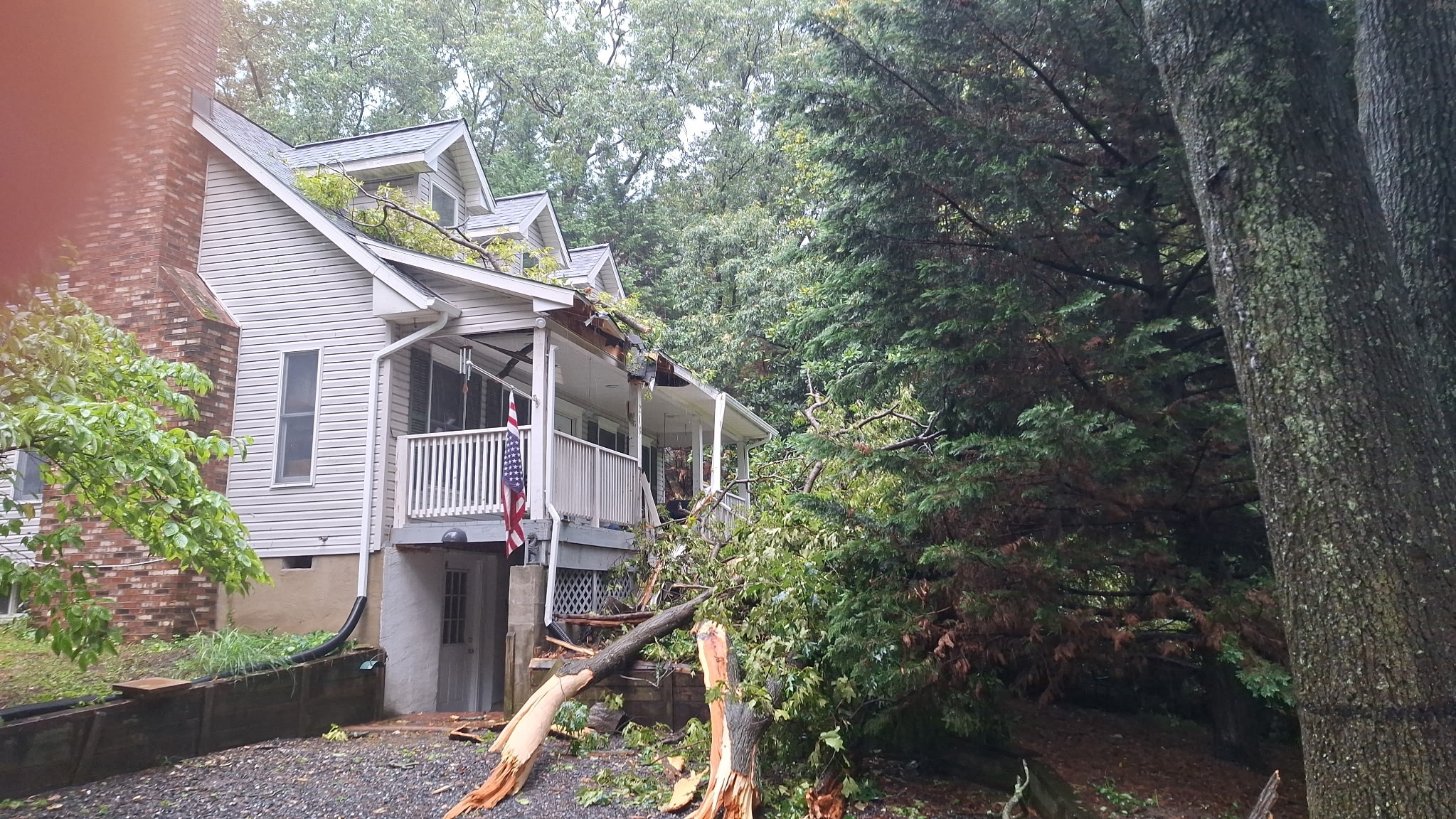 A large tree crashed onto the front of a home in Pasadena during severe thunderstorms Saturday, July 18, 2026, damaging the roof and blocking the front entrance.
