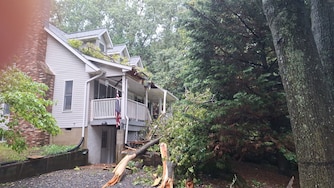 A large tree crashed onto the front of a home in Pasadena during severe thunderstorms Saturday, July 18, 2026, damaging the roof and blocking the front entrance.